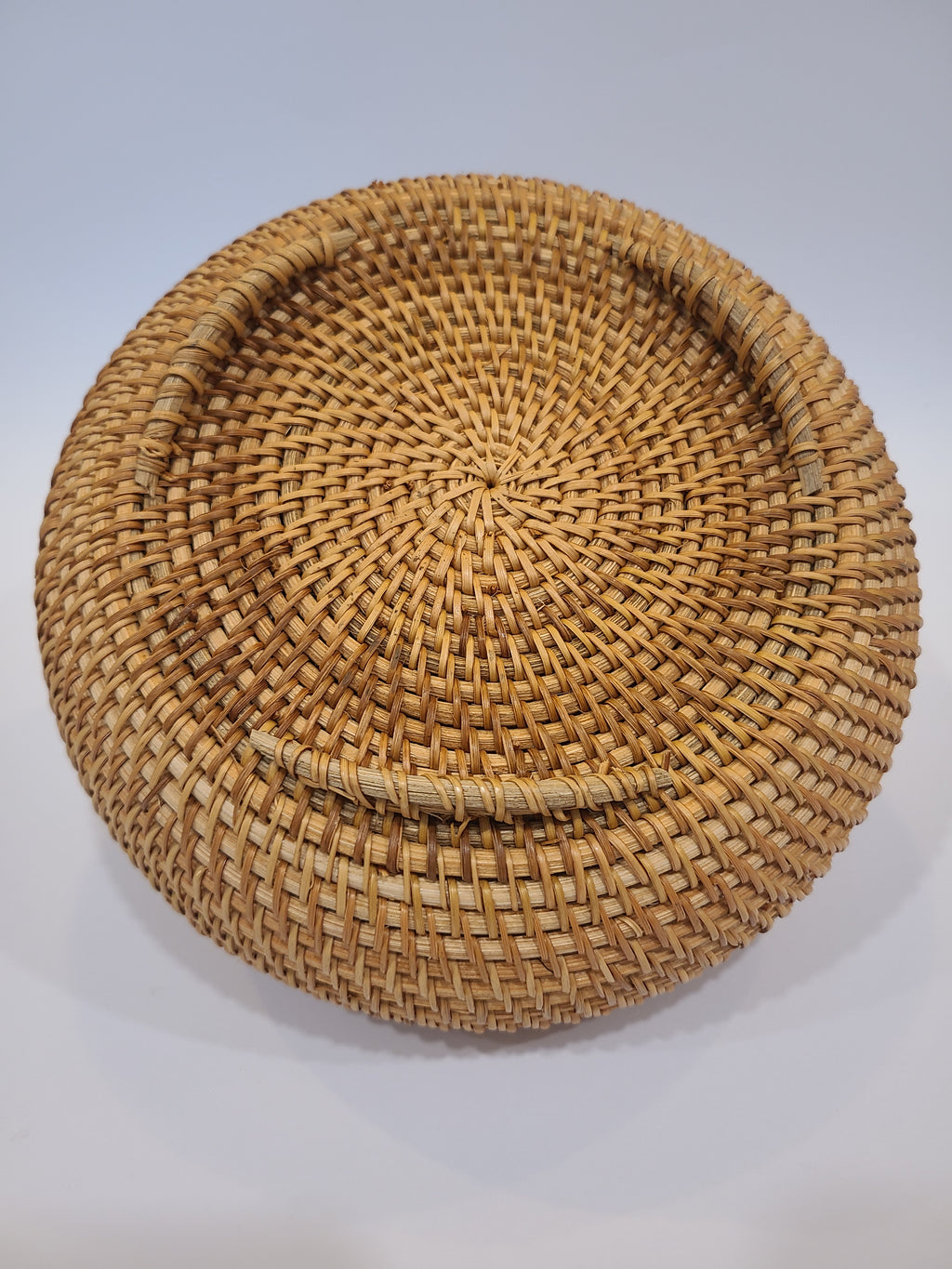 Bottom of lidded round woven natural fiber basket.