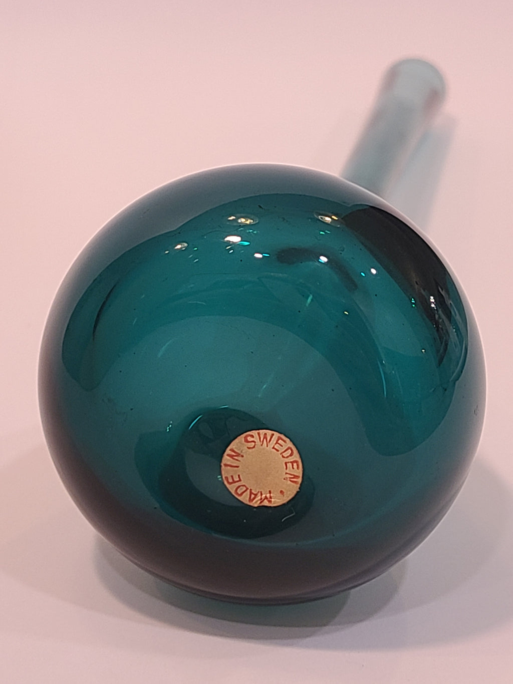 Bottom of A translucent vintage teal glass vase with a long cylindrical neck and a bulbous rounded base made in Sweden.