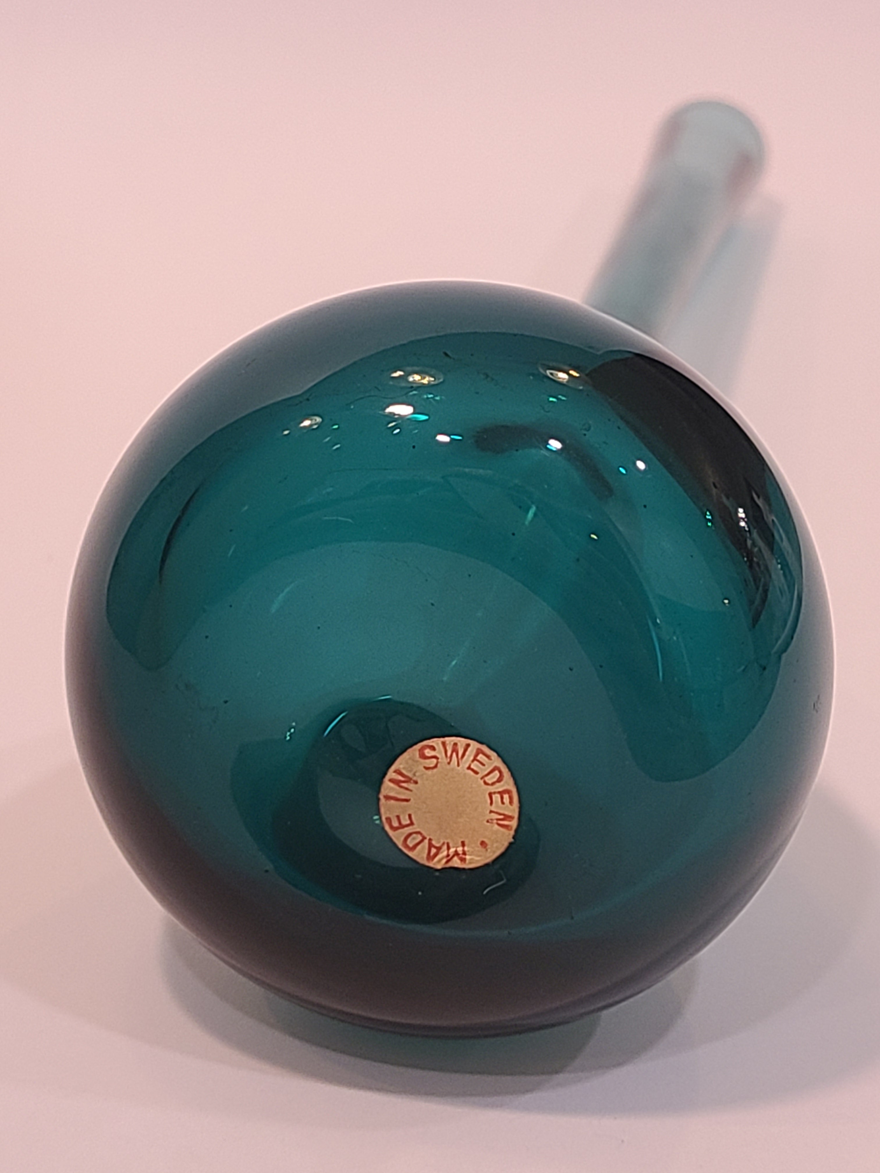 Bottom of A translucent vintage teal glass vase with a long cylindrical neck and a bulbous rounded base made in Sweden.