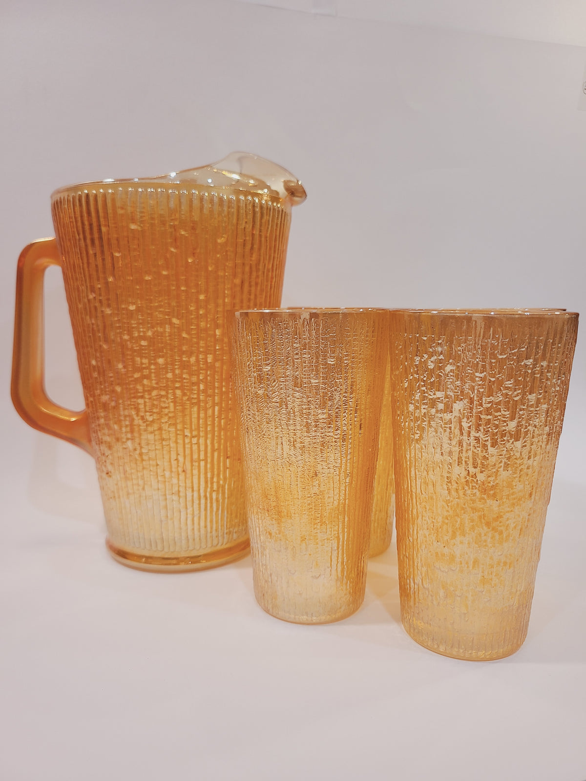 Jeannette Glass Depression-era carnival glass pitcher and 5 glasses set in Marigold Tree Bark pattern, iridescent orange-gold, USA circa 1920s–1930s.