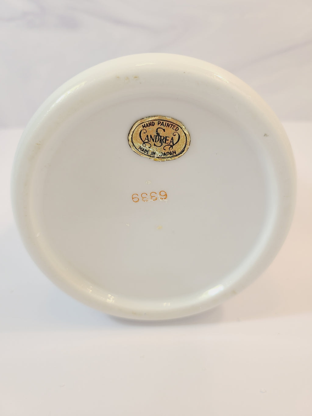 Bottom of Andrea by Sadek vintage white porcelain vase made in Japan hand-painted with light blue floral motifs, gold accents, and a blue-and-gold patterned band at the neck. 