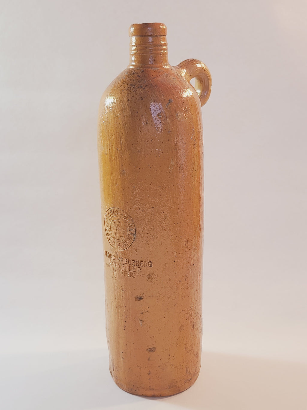 Antique 19th century terracotta colored stoneware bottle stamped with the name of Georg Kreuzberg and the Apollinaris Brunnen.
