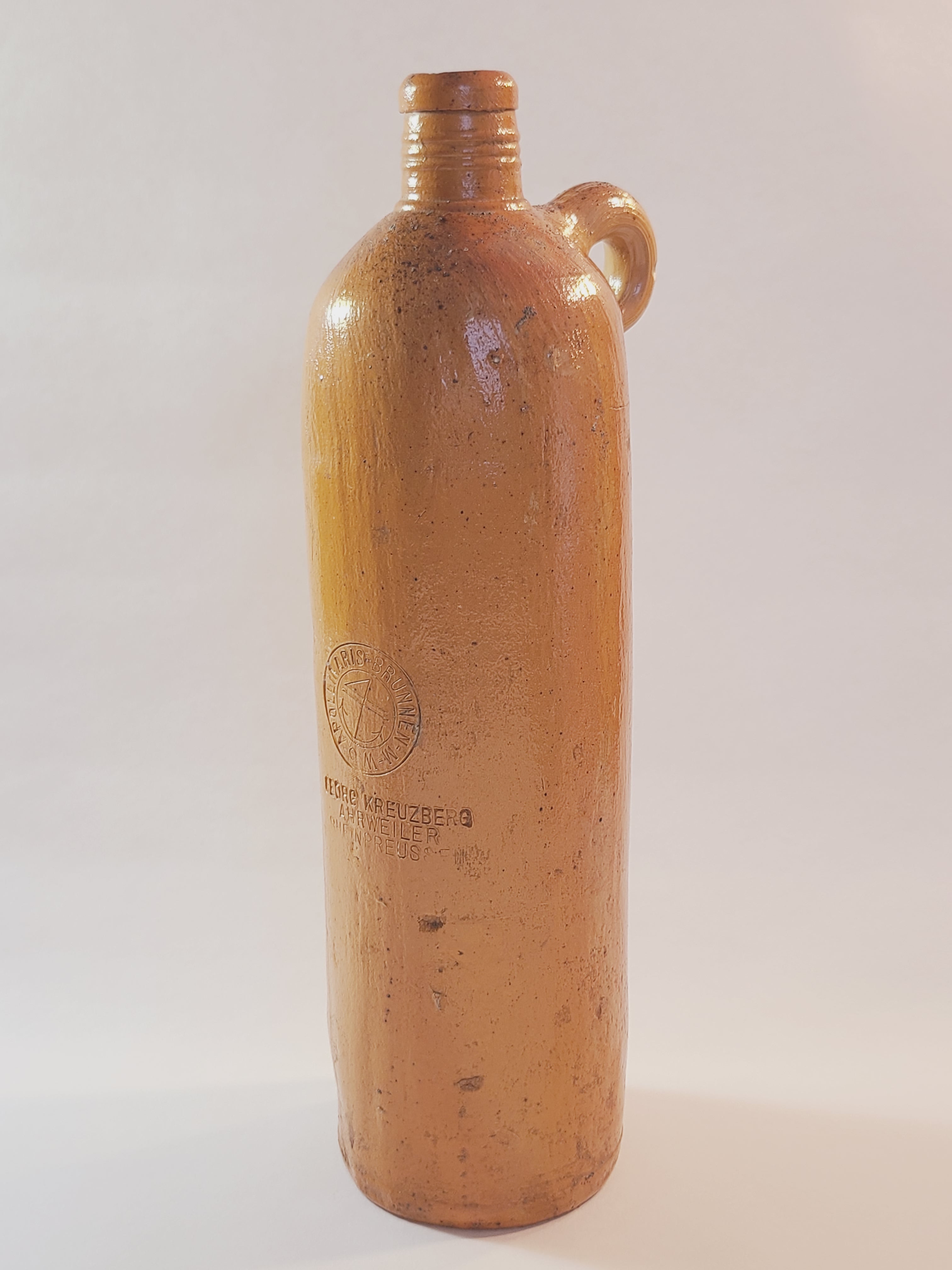 Antique 19th century terracotta colored stoneware bottle stamped with the name of Georg Kreuzberg and the Apollinaris Brunnen.