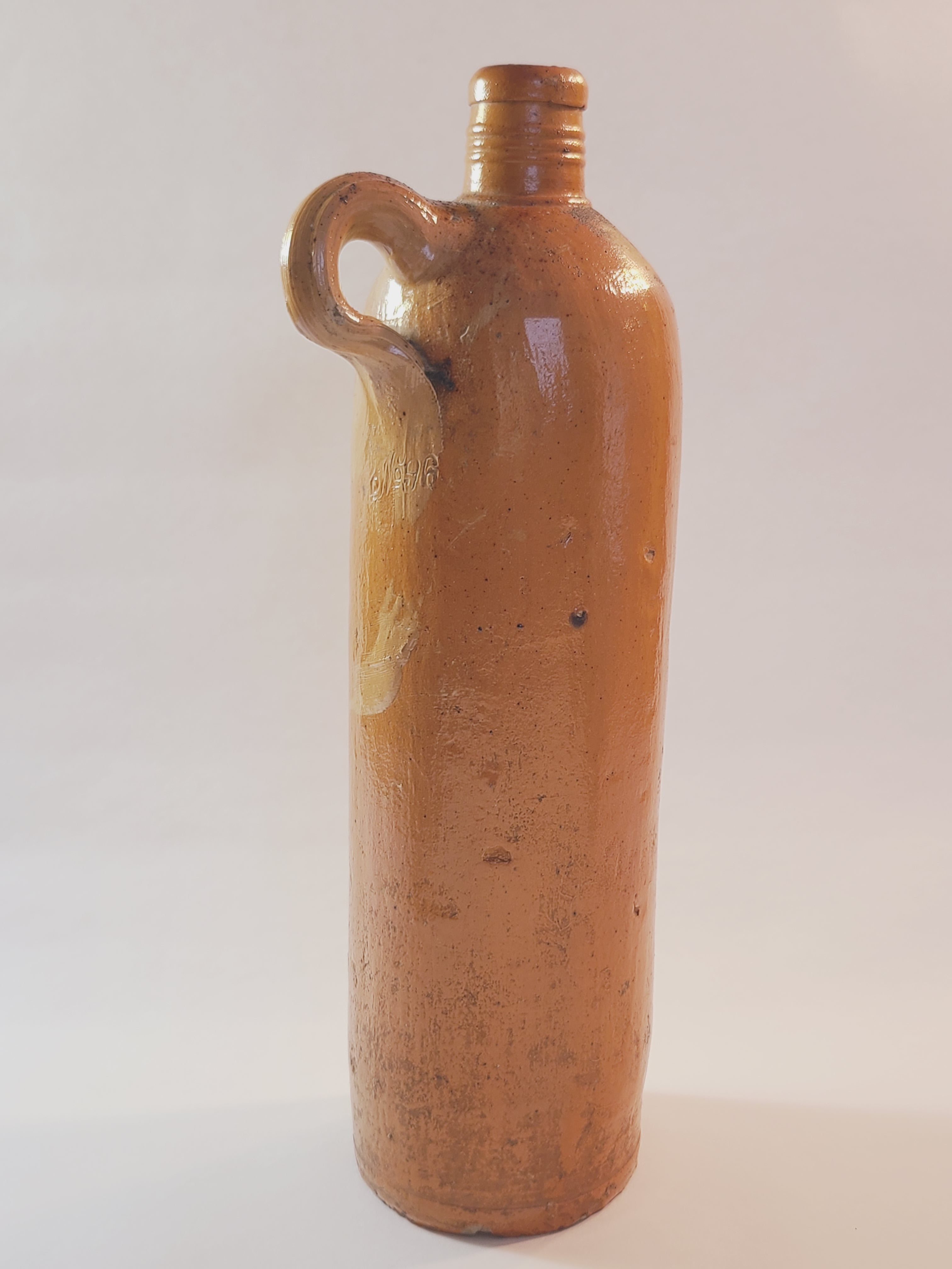 Antique 19th century terracotta colored stoneware bottle stamped with the name of Georg Kreuzberg and the Apollinaris Brunnen showing finger loop.