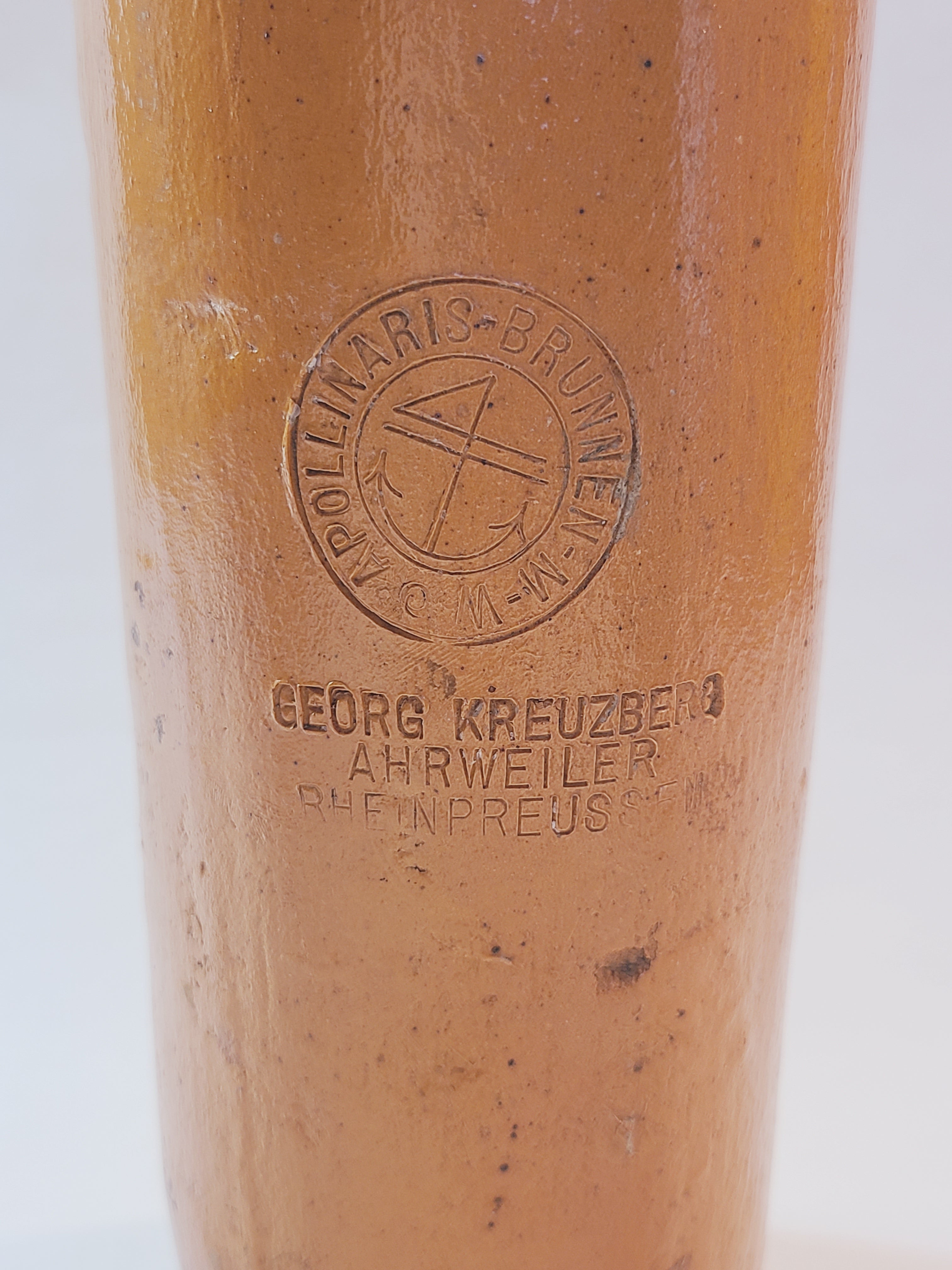 Close up of Antique 19th century terracotta colored stoneware bottle stamped with the name of Georg Kreuzberg and the Apollinaris Brunnen.