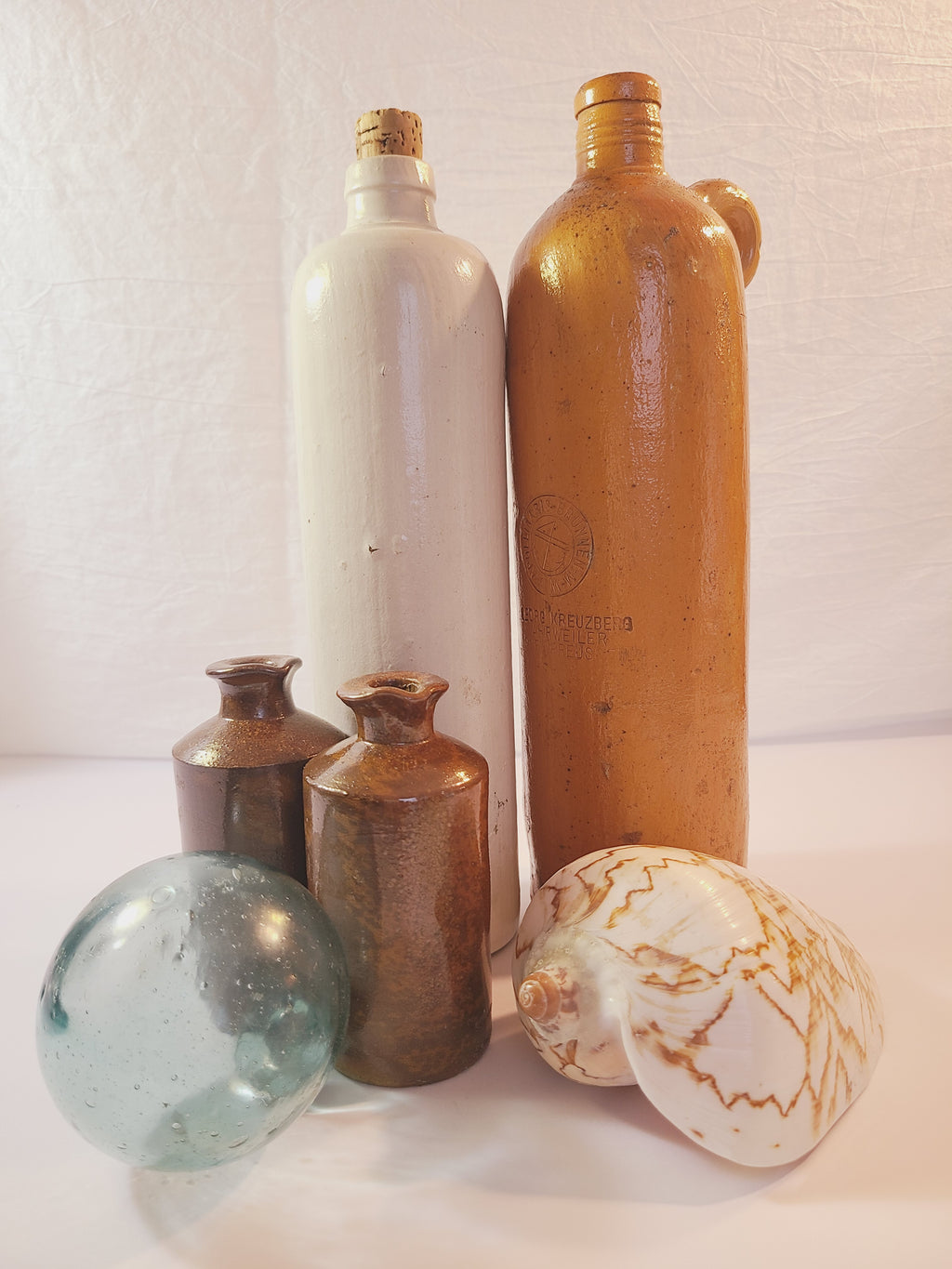 Antique Lovatt & Lovatt salt-glazed stoneware ink bottles with vintage stoneware bottles, glass fishing float, and shell — coastal decor