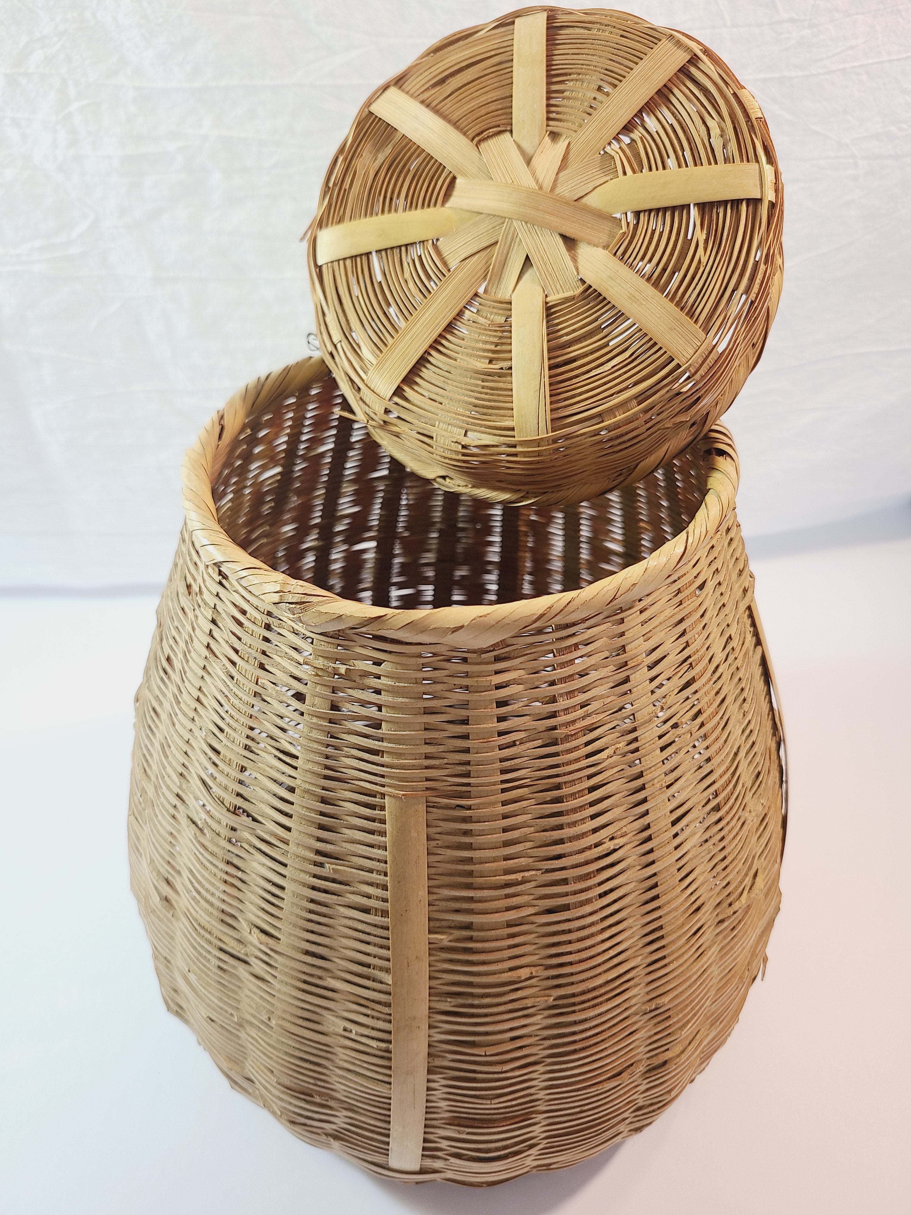 A natural woven wicker basket with a matching round lid, shown against a plain white background.