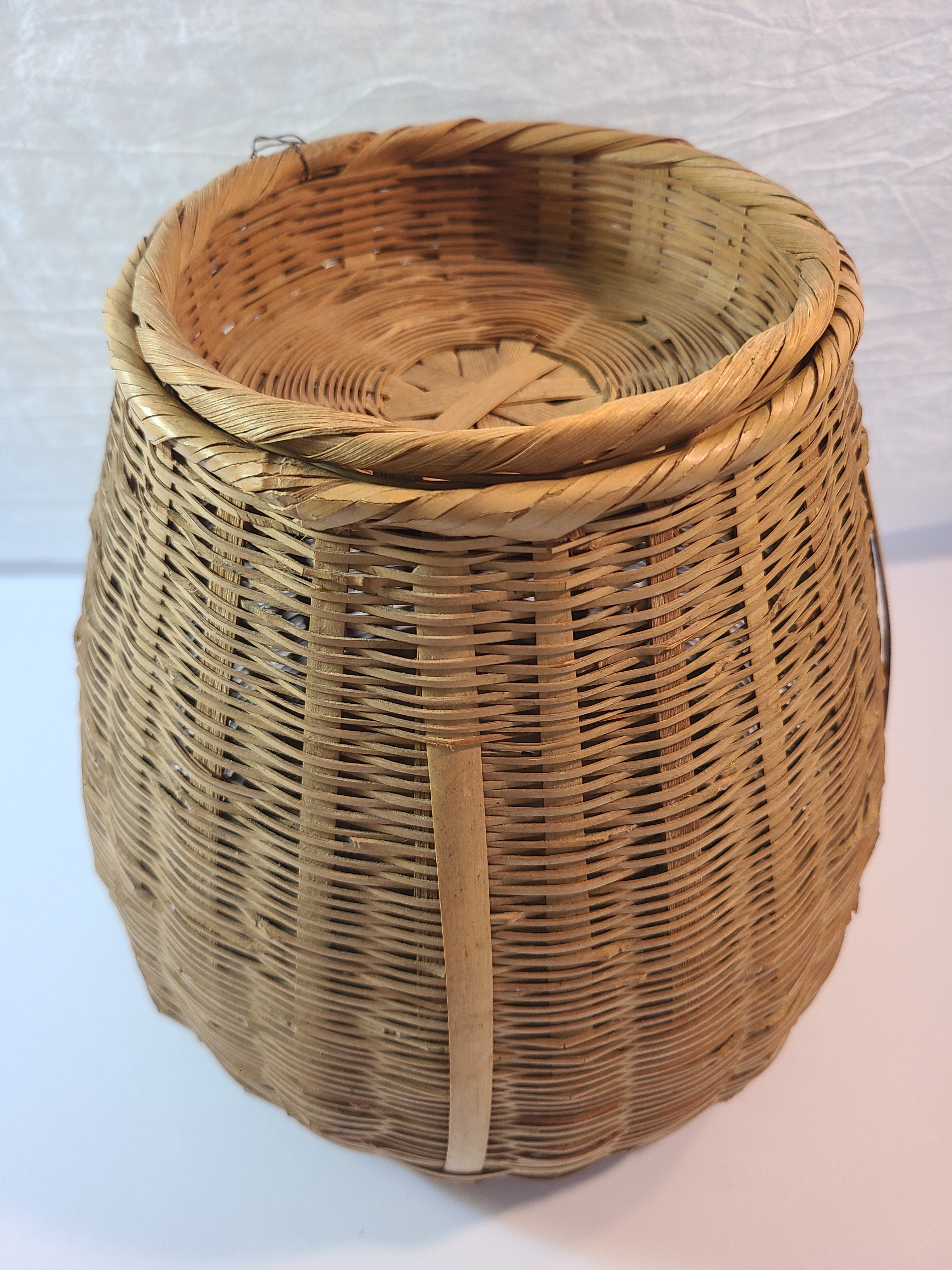 A natural woven wicker basket with a fitted lid, photographed against a plain light background.