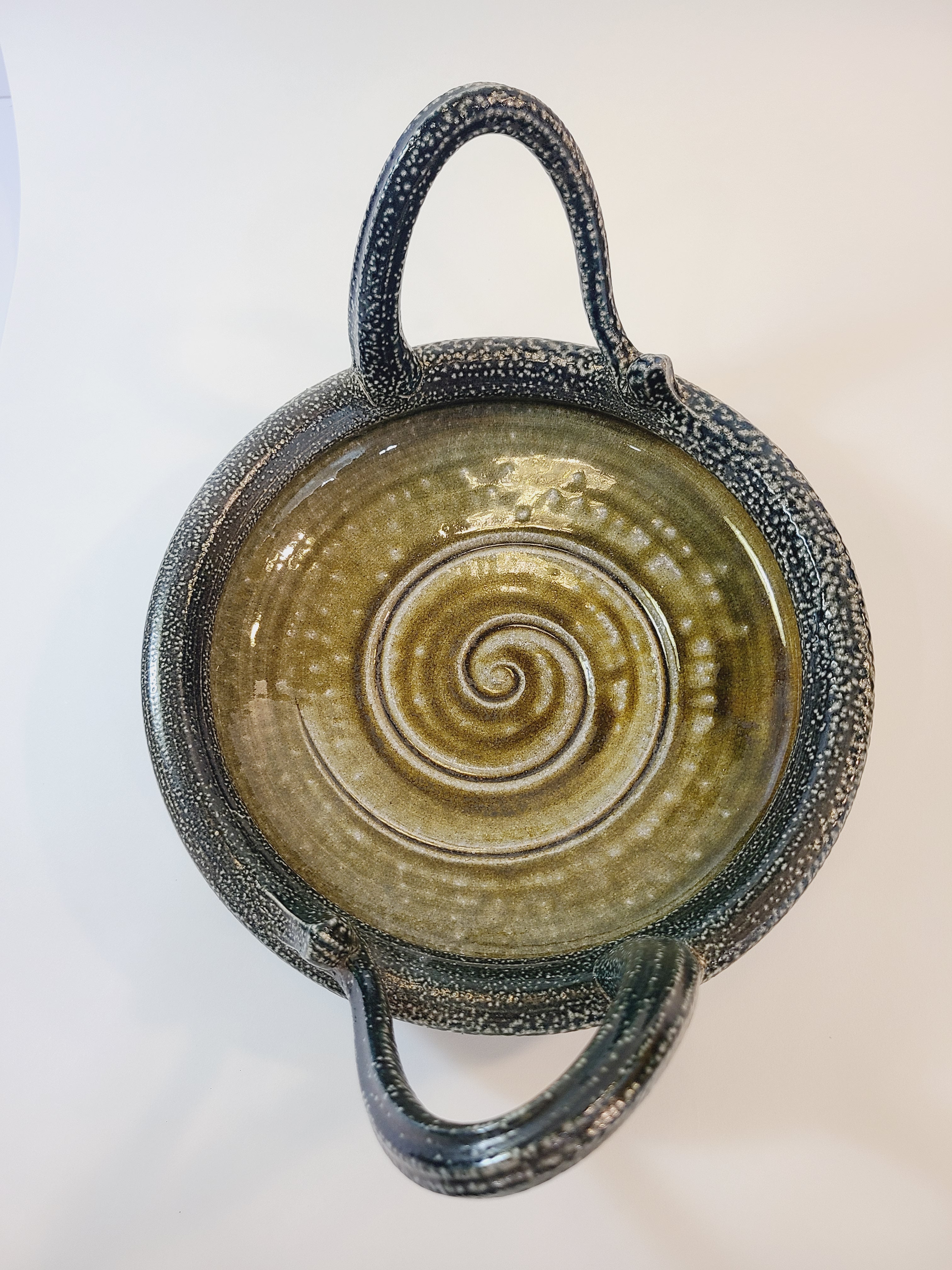 Overhead view of Jon Faulkner studio Pottery Bowl in shades of olive green and darkest blue or black on a white background.
