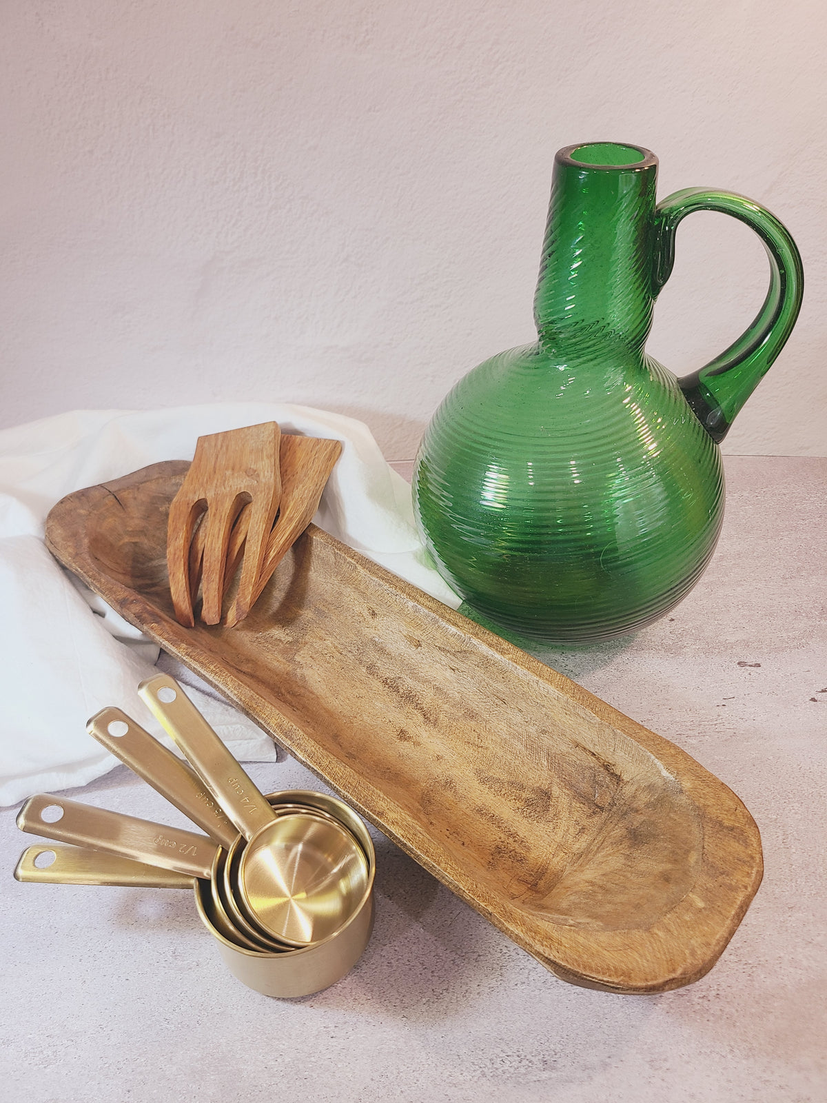 Emerald green handblown glass jug styled with rustic wood bowl and brass kitchen accents, coastal vintage home decor