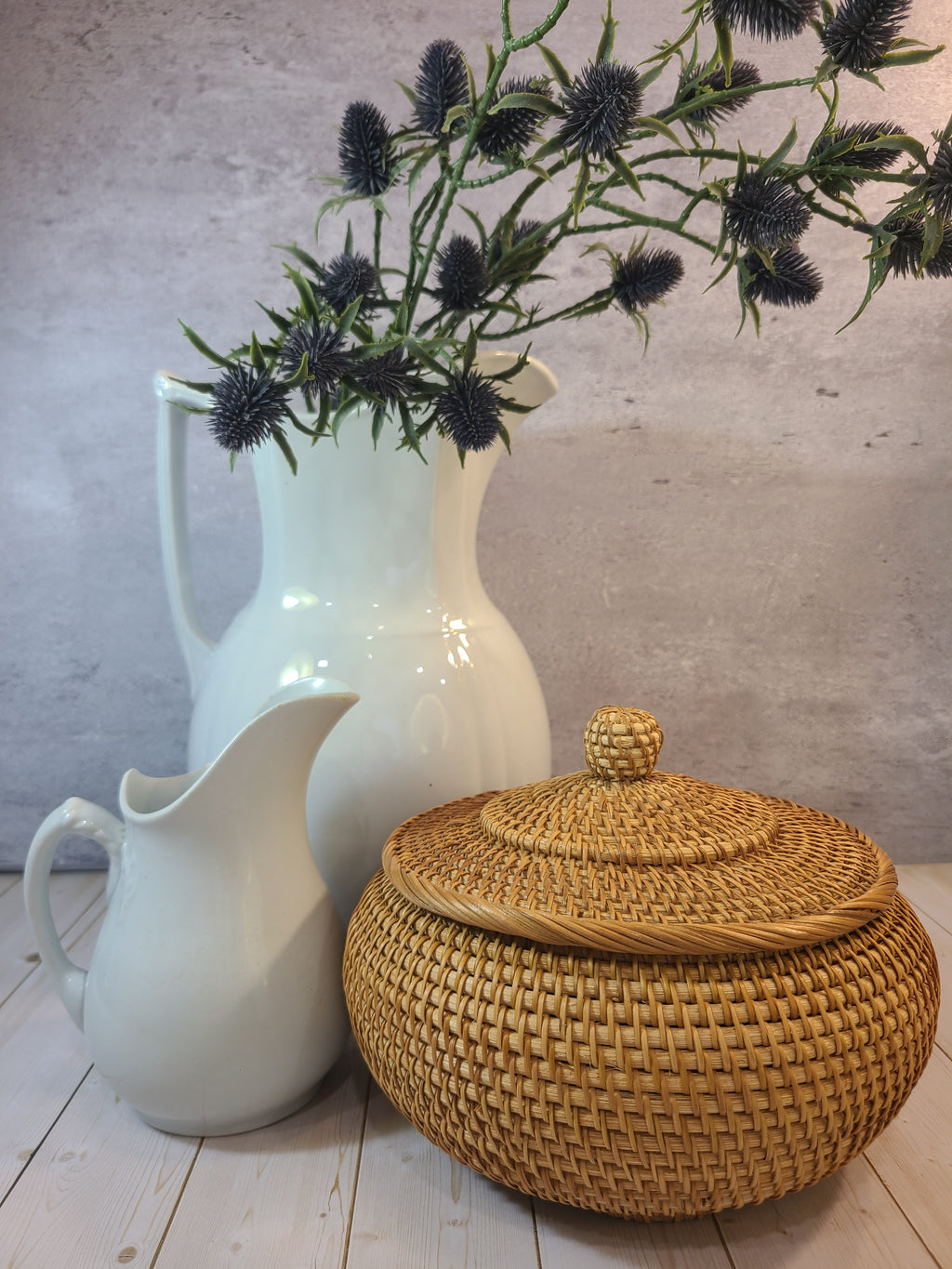 Round lidded woven basket styled with large and small ironstone pitchers.