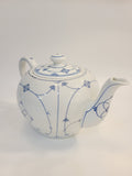 A vintage white ceramic teapot with a lid, decorated with delicate blue floral and vine patterns, shown against a plain white background.