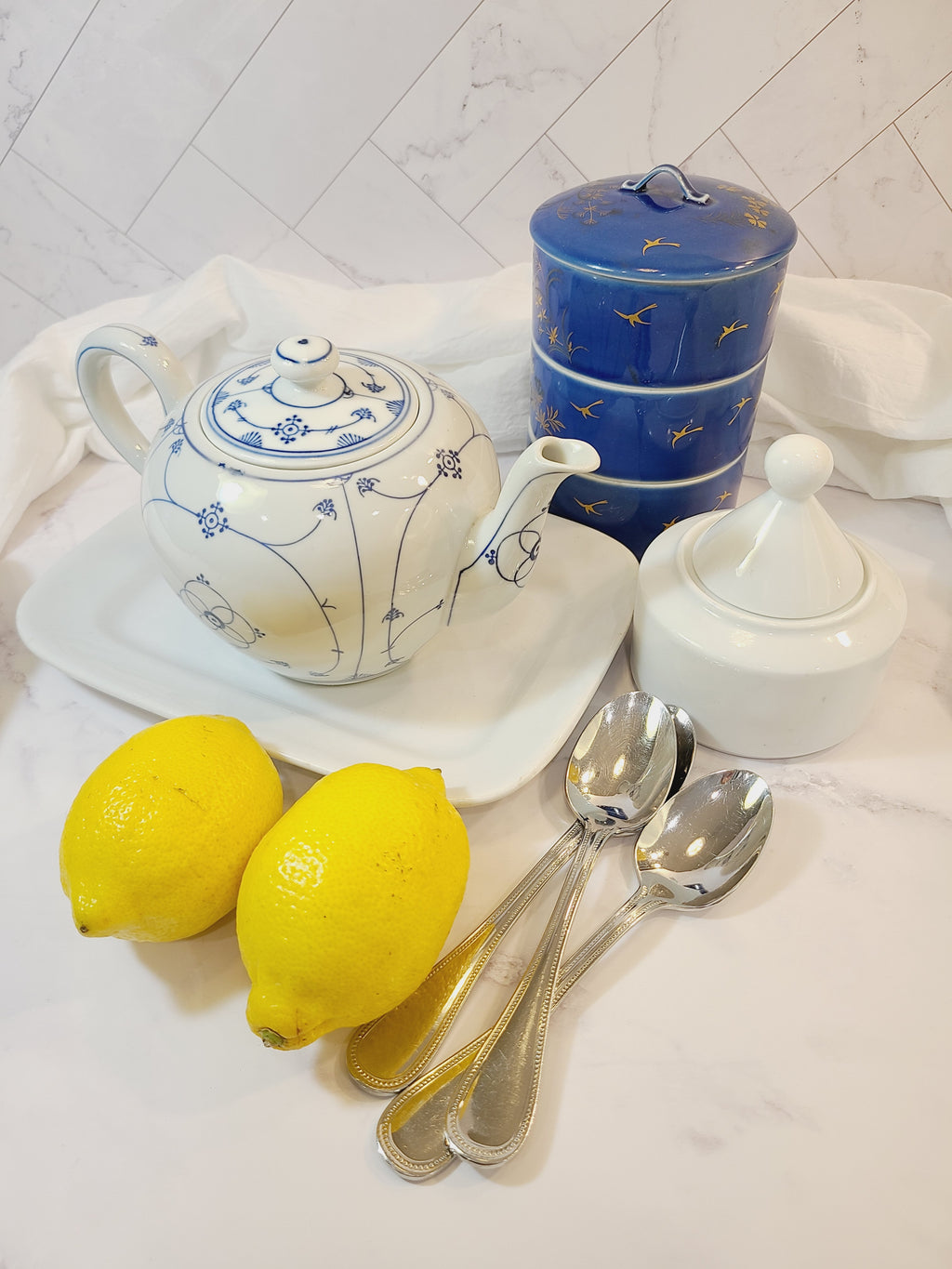 Vintage Fukagawa Seiji 3-Tier Stacking Bowl Set with Lid in lapis blue with gold accents displayed in a table setting.