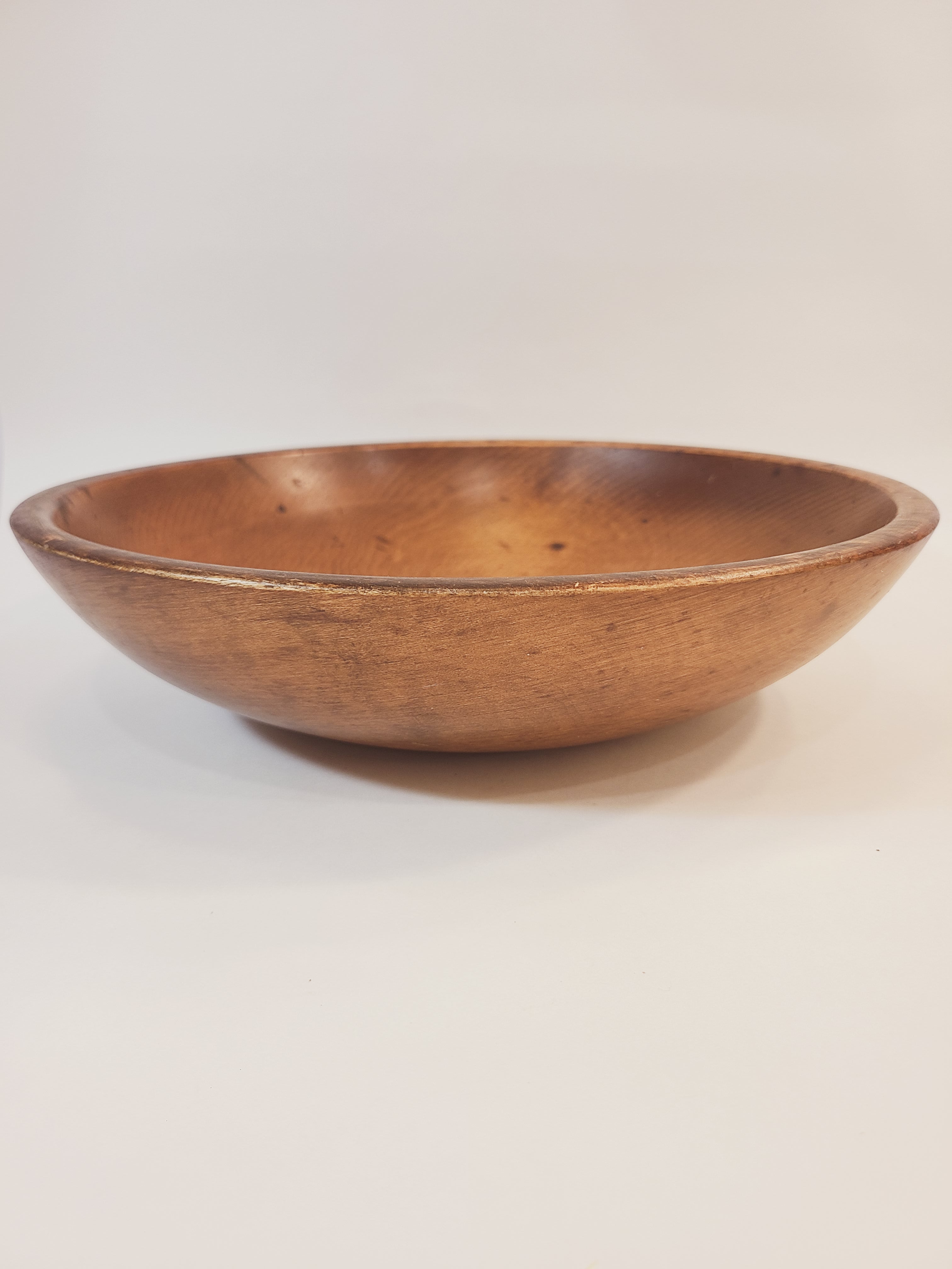 A vintage rustic wooden bowl with a warm brown finish, shown from a side profile against a plain off-white background.