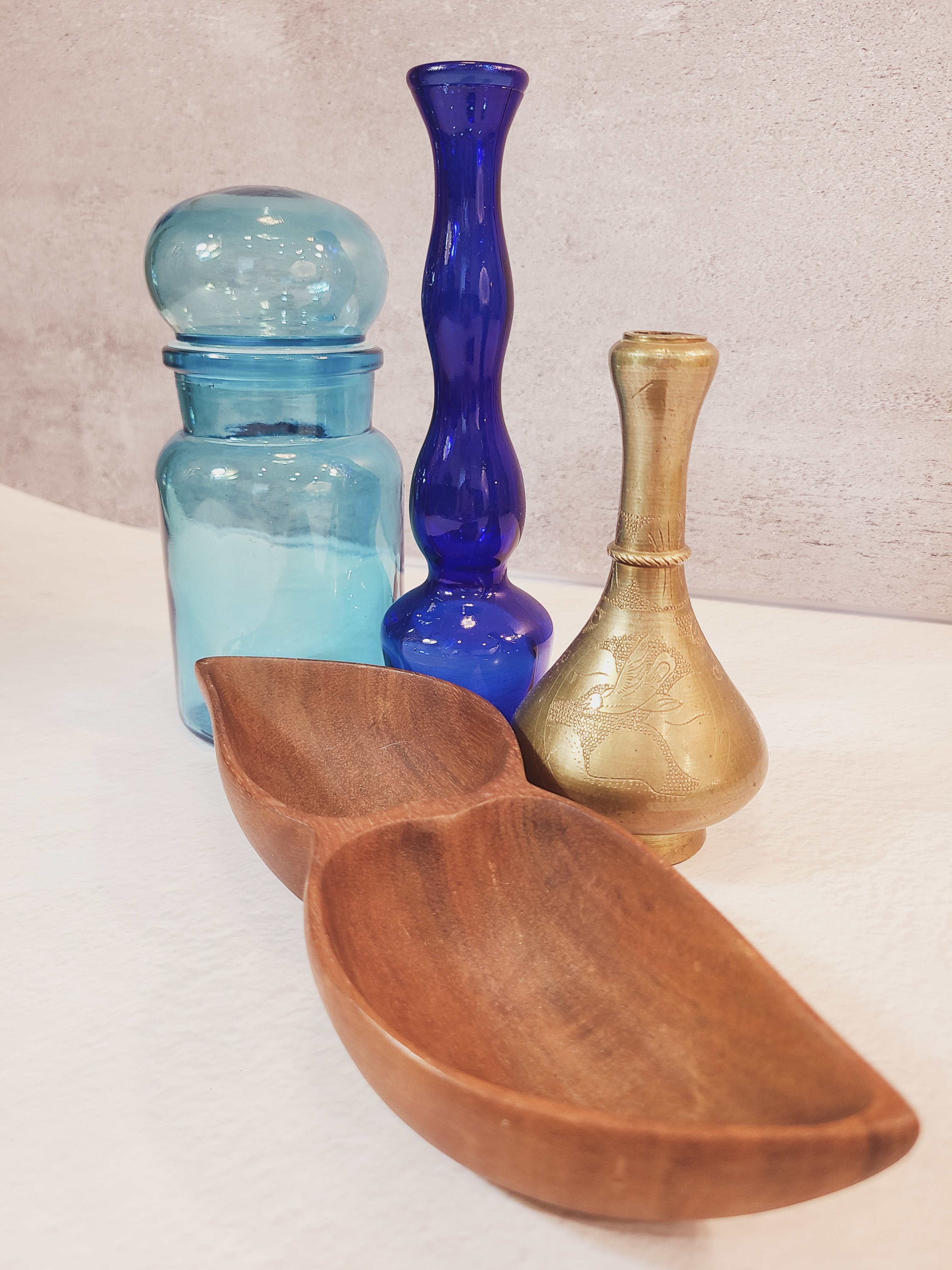 Vintage mid-century divided wood bowl in the foreground, styled with brass vase, glass bud vase, and glass jar.