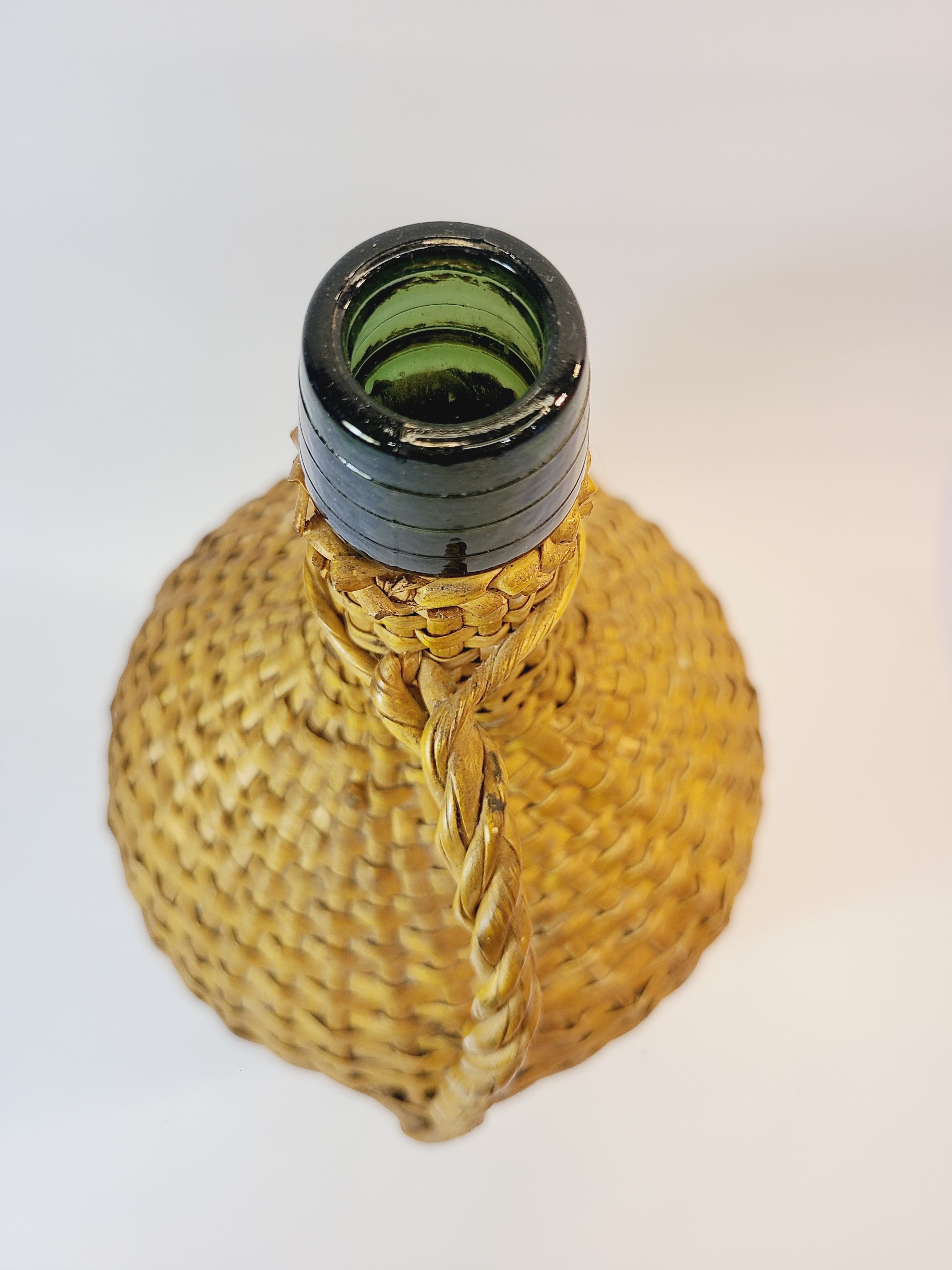 Top view of Vintage demijohn green glass with original rattan wrapping on plain background.