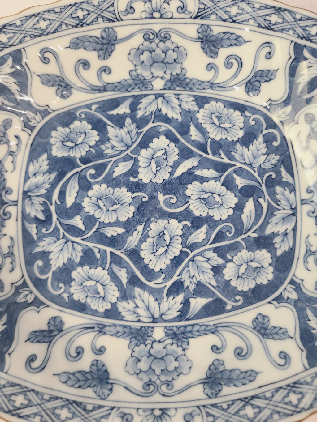 Close up of pattern of A vintage rectangular blue and white porcelain serving platter featuring an intricate floral and vine pattern made in Japan.