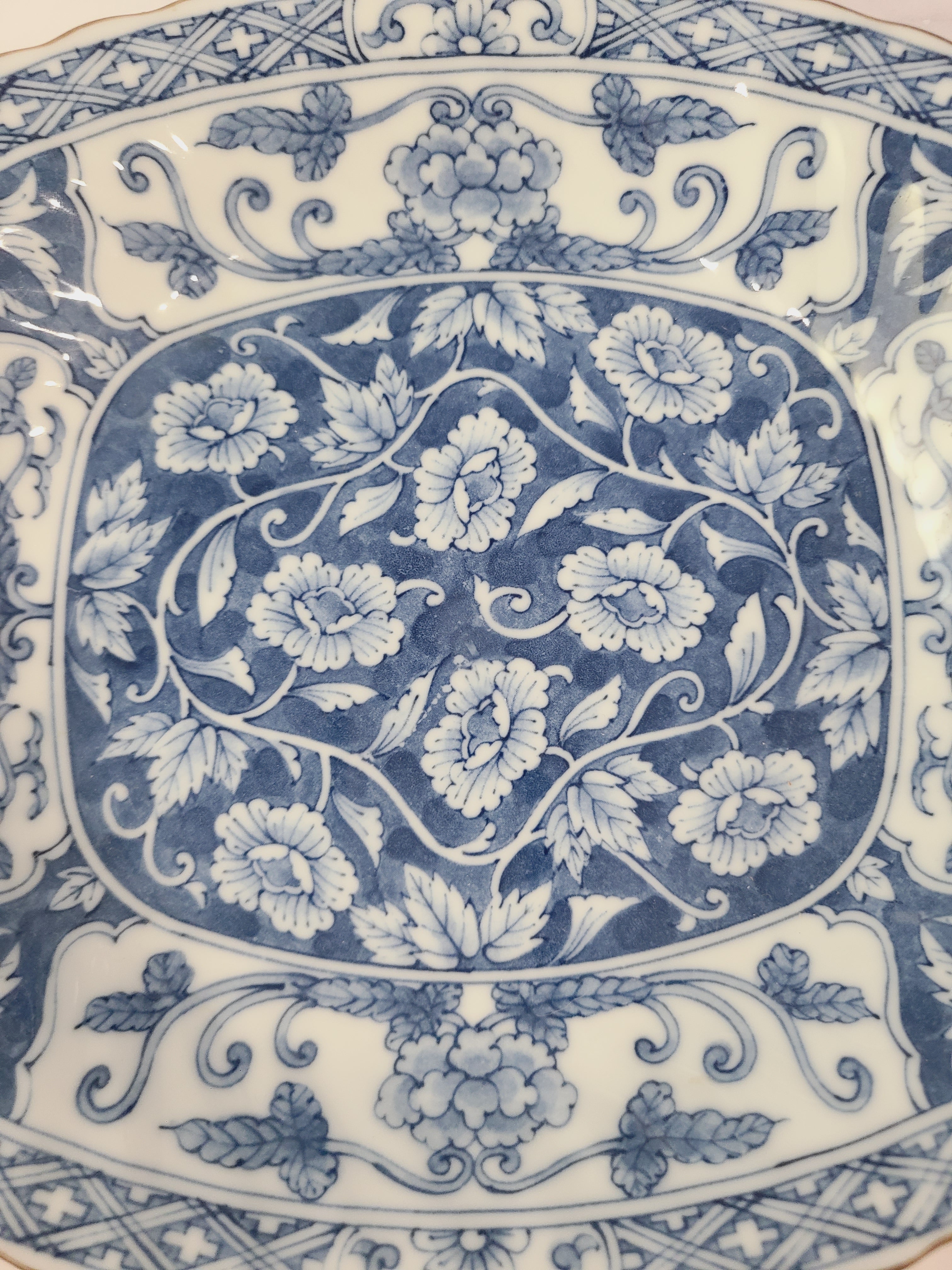 Close up of pattern of A vintage rectangular blue and white porcelain serving platter featuring an intricate floral and vine pattern made in Japan.