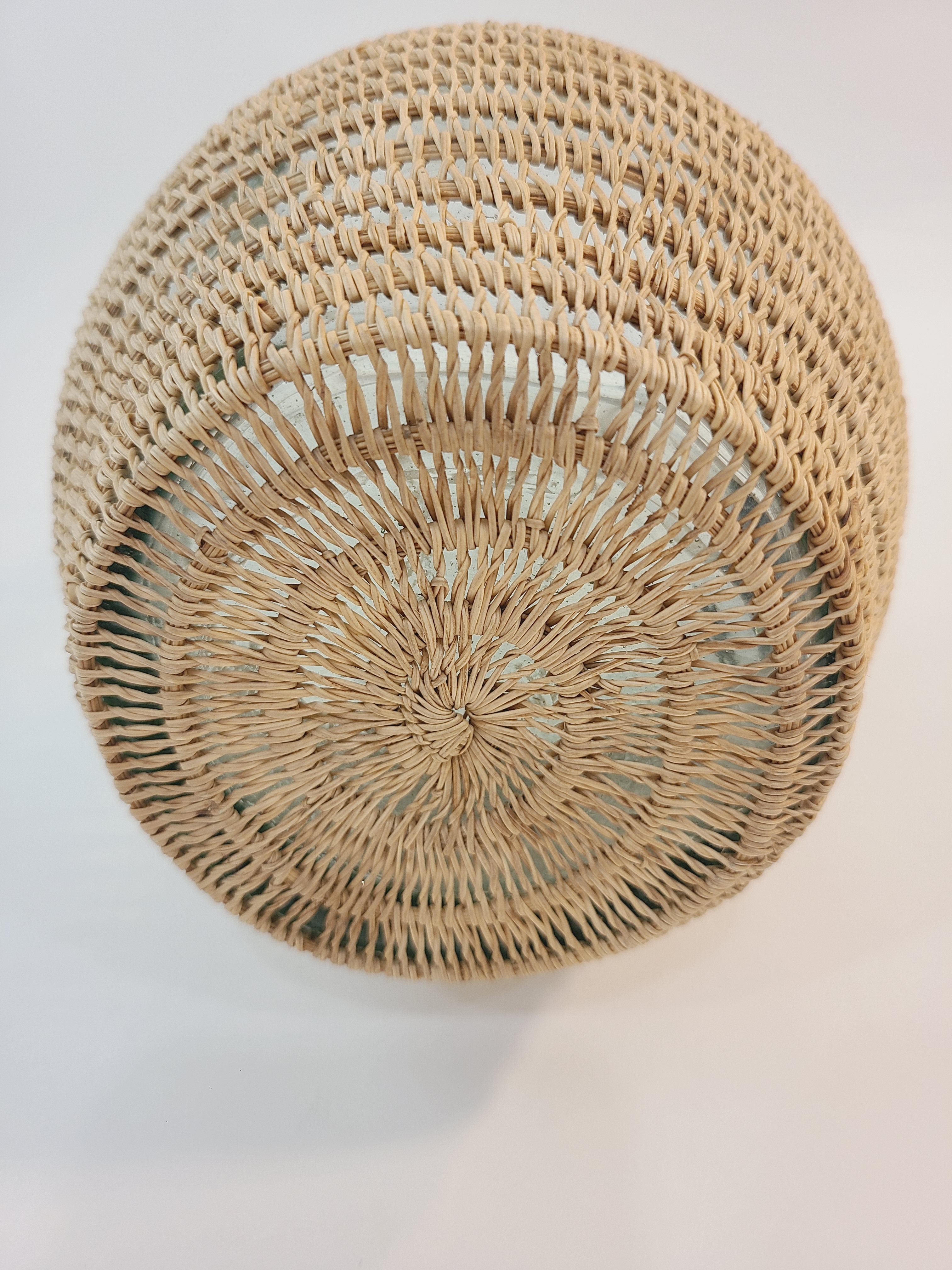 Bottom of a vintage clear glass pitcher wrapped in a woven natural fiber.