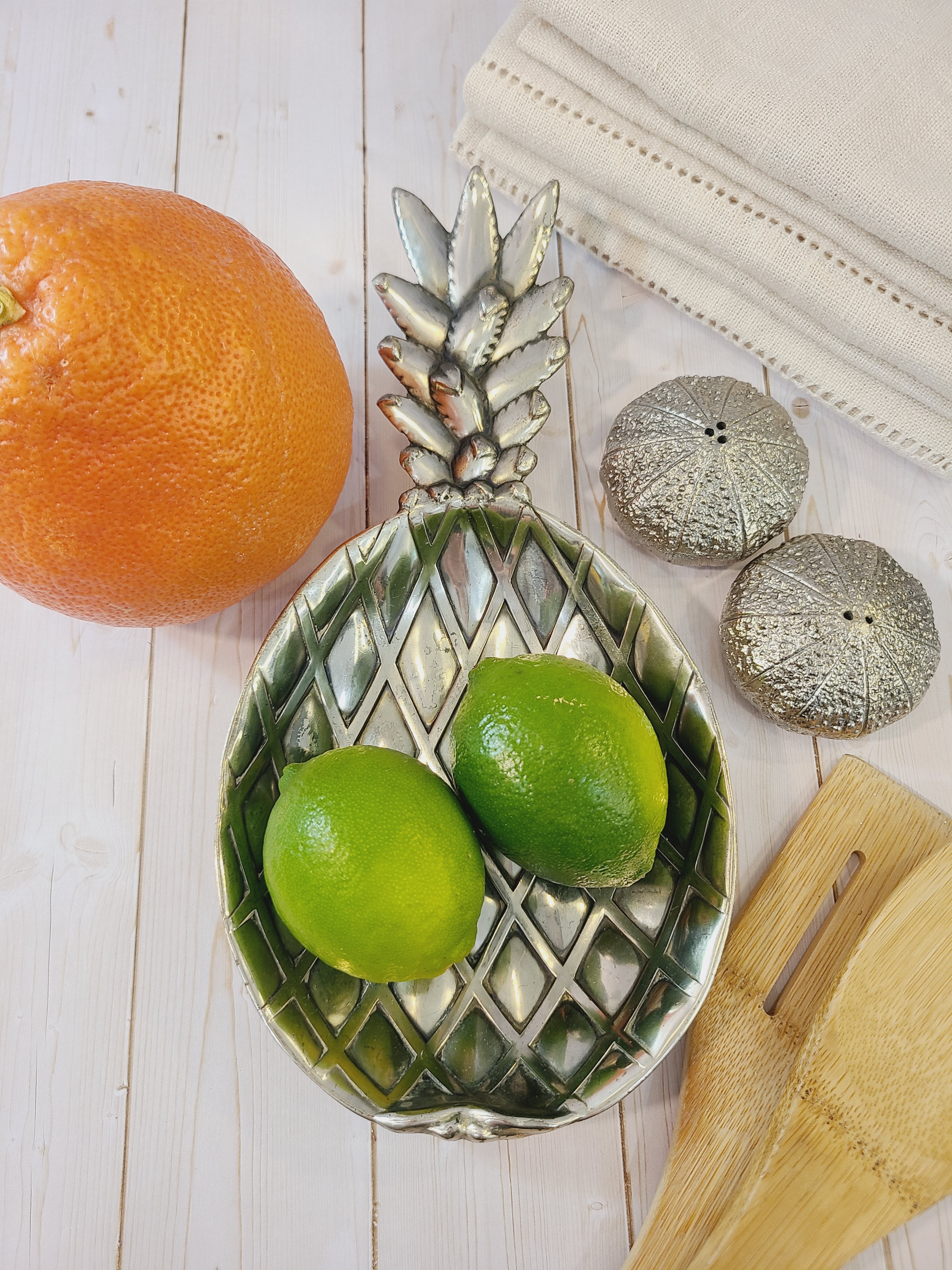 Vintage pineapple silver tone metal dish made in Japan by Matsumoto for the Eleanor retail line displayed with citrus fruit.