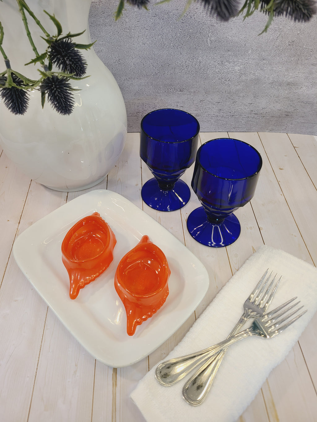 Antique white Alfred Meakin Royal Ironstone Platter styled with cobalt blue goblets, crab dishes, linen napkin, silverware, ironstone pitcher.