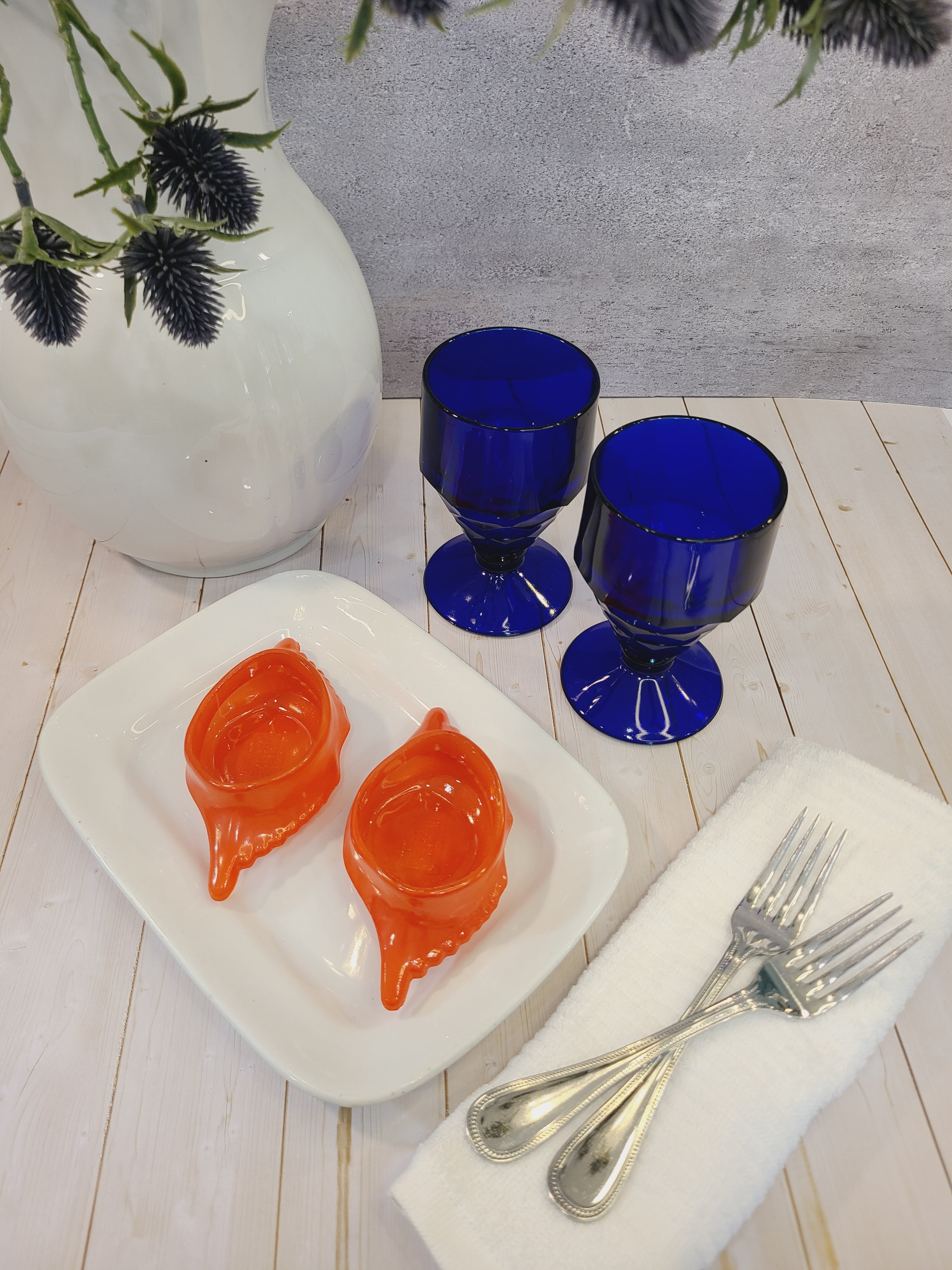 Antique white Alfred Meakin Royal Ironstone Platter styled with cobalt blue goblets, crab dishes, linen napkin, silverware, ironstone pitcher.
