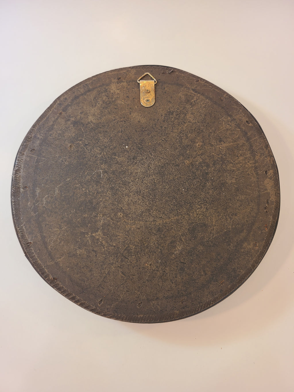 Back of A vintage round wall mirror with an intricate dark brown cane frame.