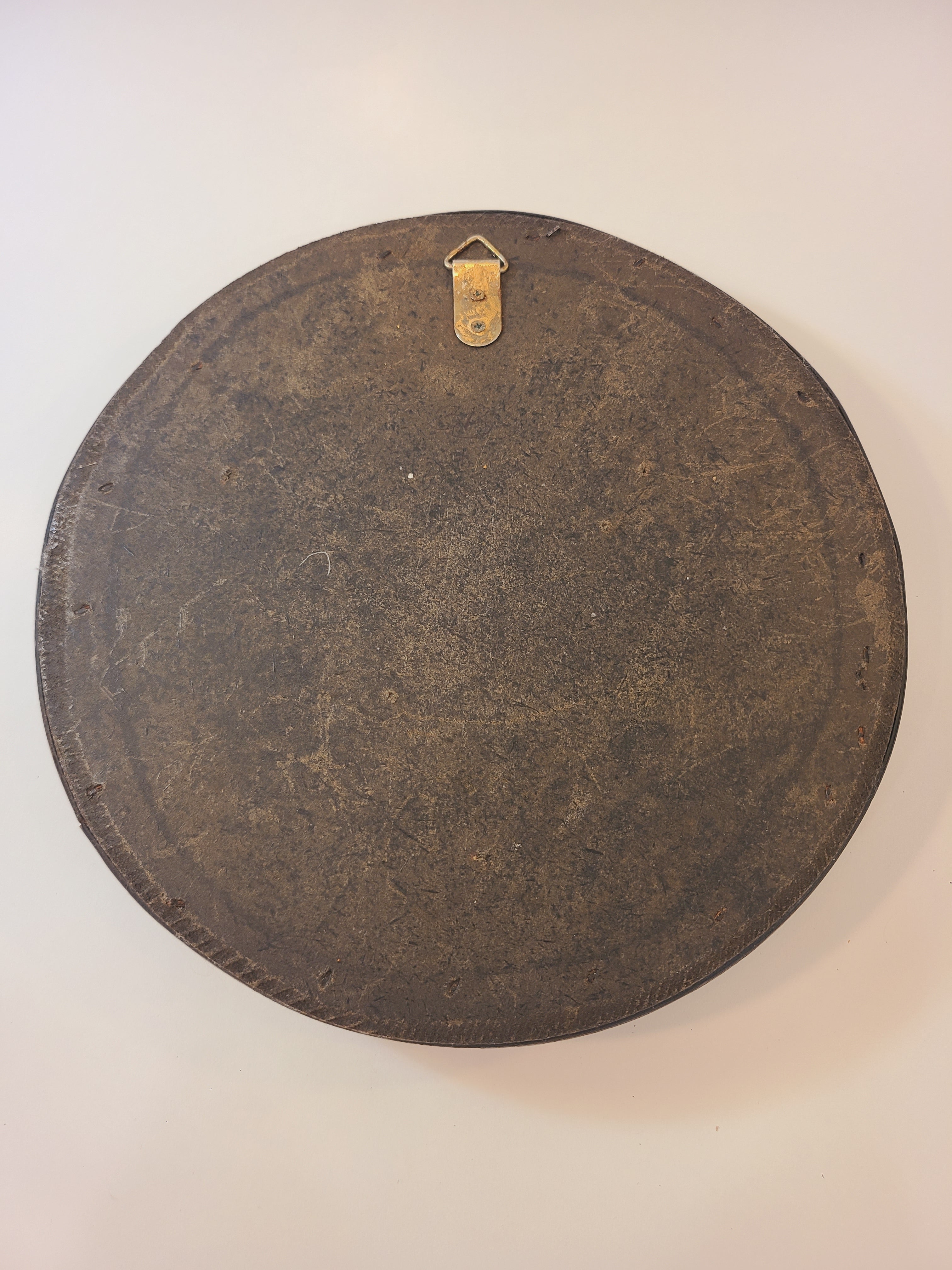 Back of A vintage round wall mirror with an intricate dark brown cane frame.