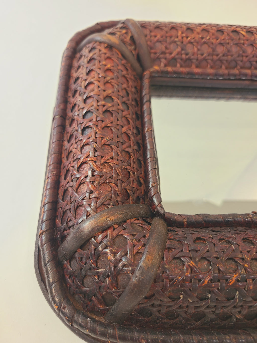 Close up of dark brown cane frame on A vintage square mirror.