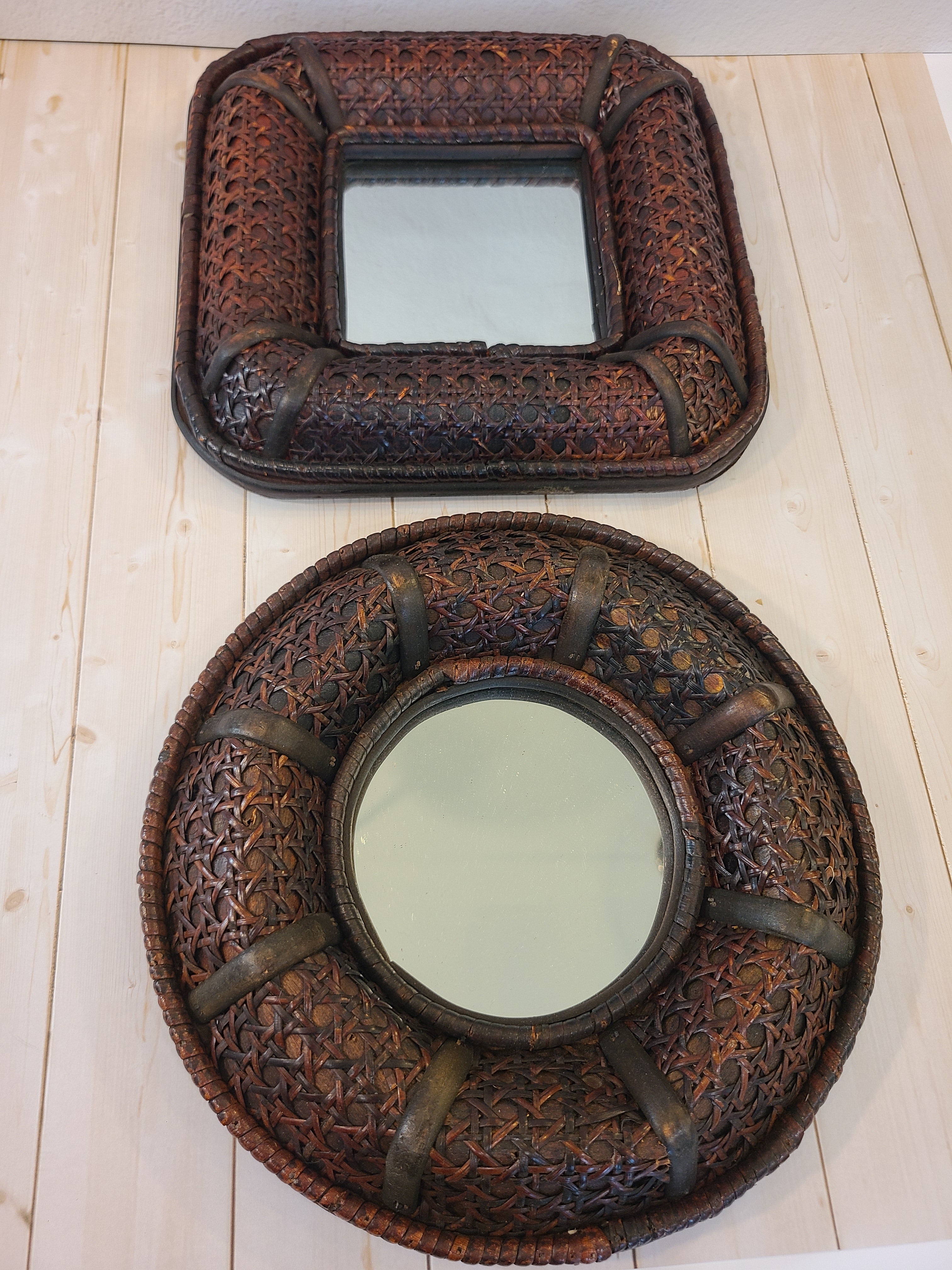 A vintage round wall mirror with an intricate dark brown cane frame photographed with a matching square mirror.