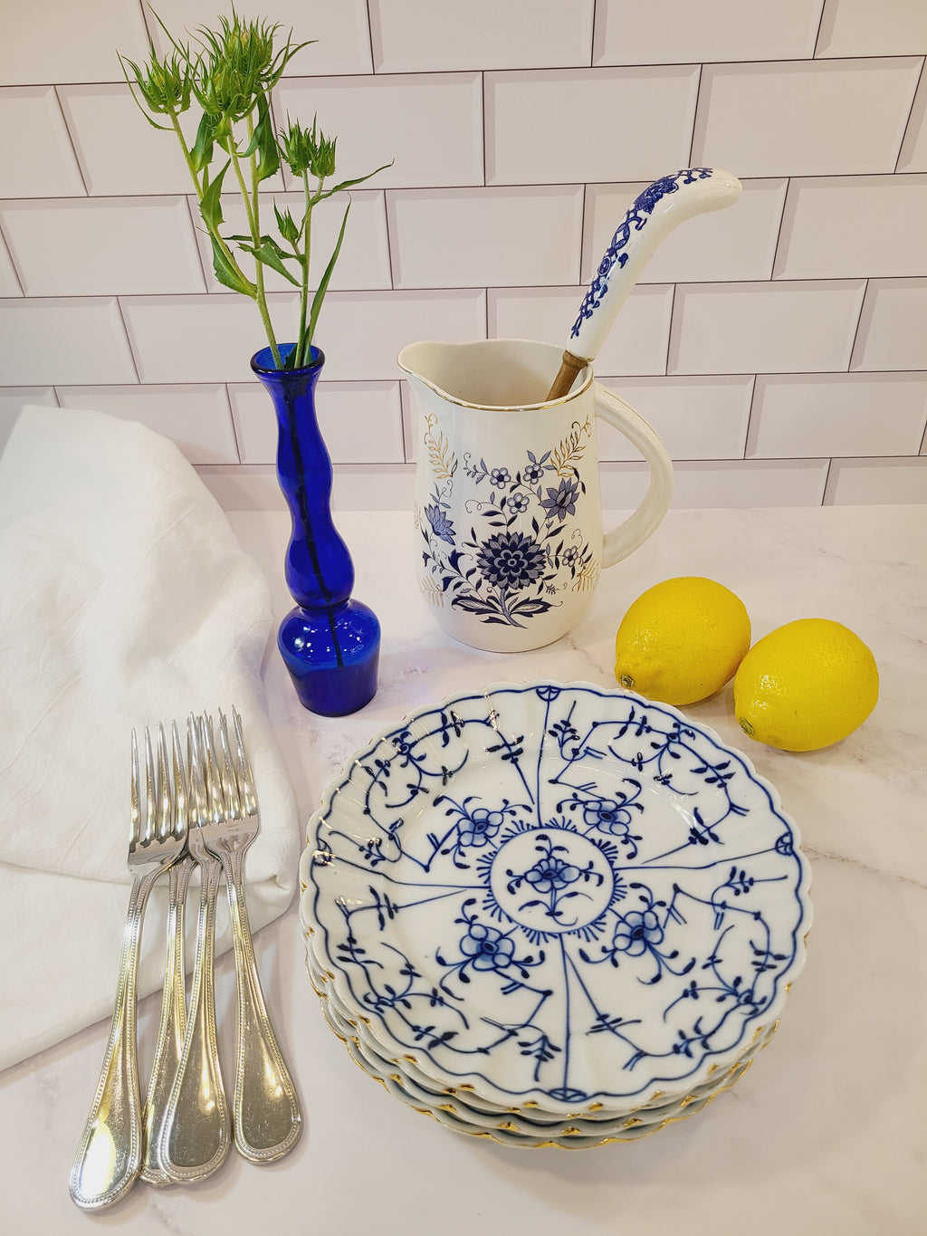 Antique Royal Tettau Blue and White Porcelain Plate displayed with silverware, pitcher, lemons, bud vase.