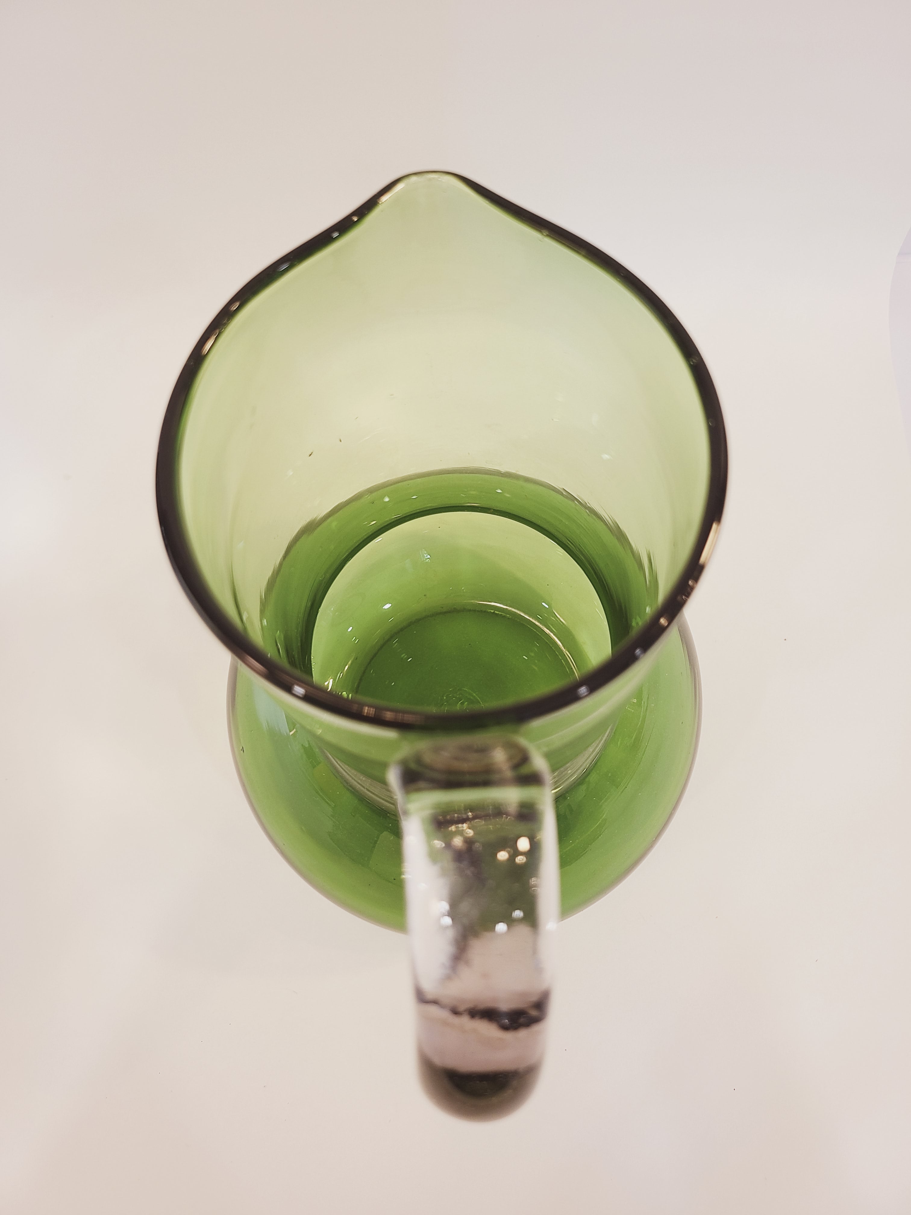 A vintage green glass pitcher shown from a top-down perspective on a white background.