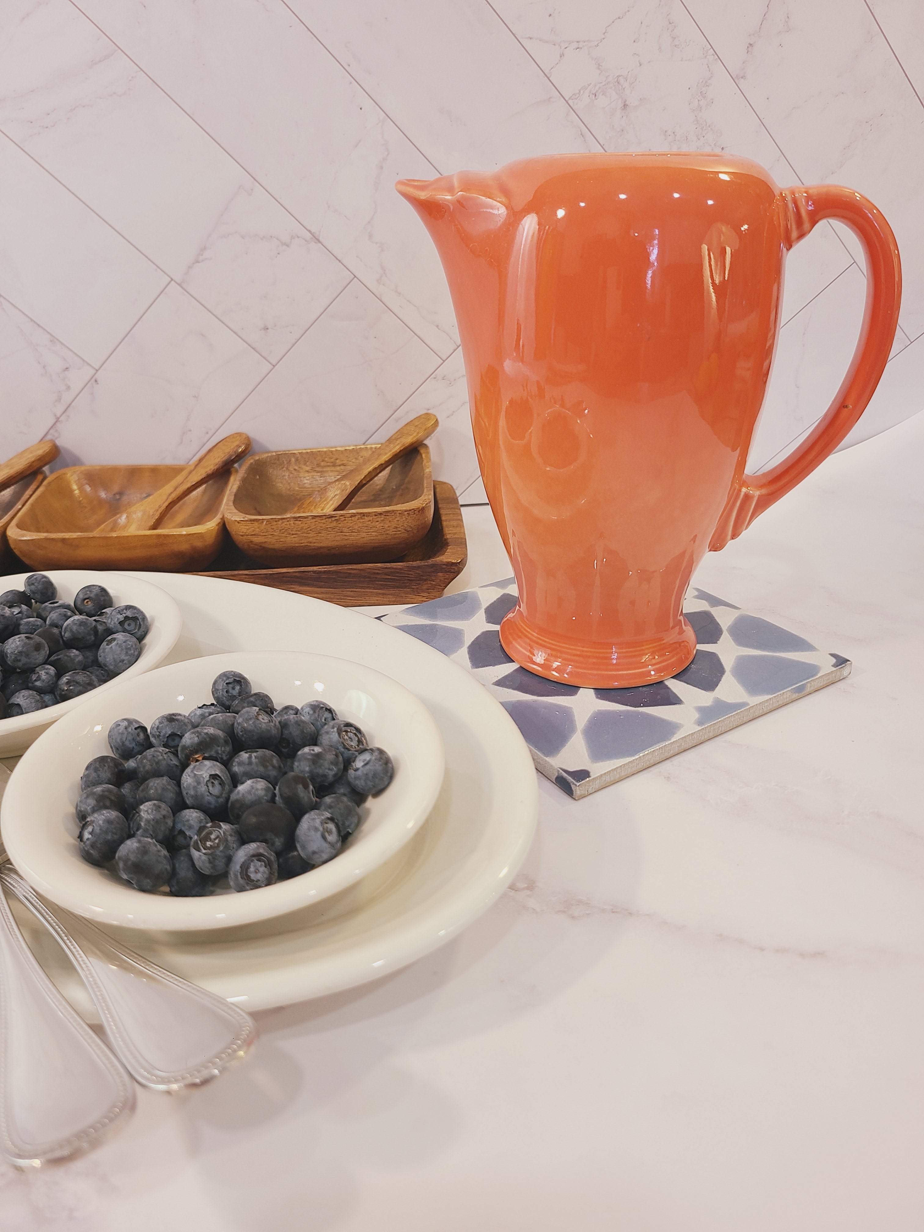 Fiesta carafe in color Persimmon styled with blueberries in white dishes.