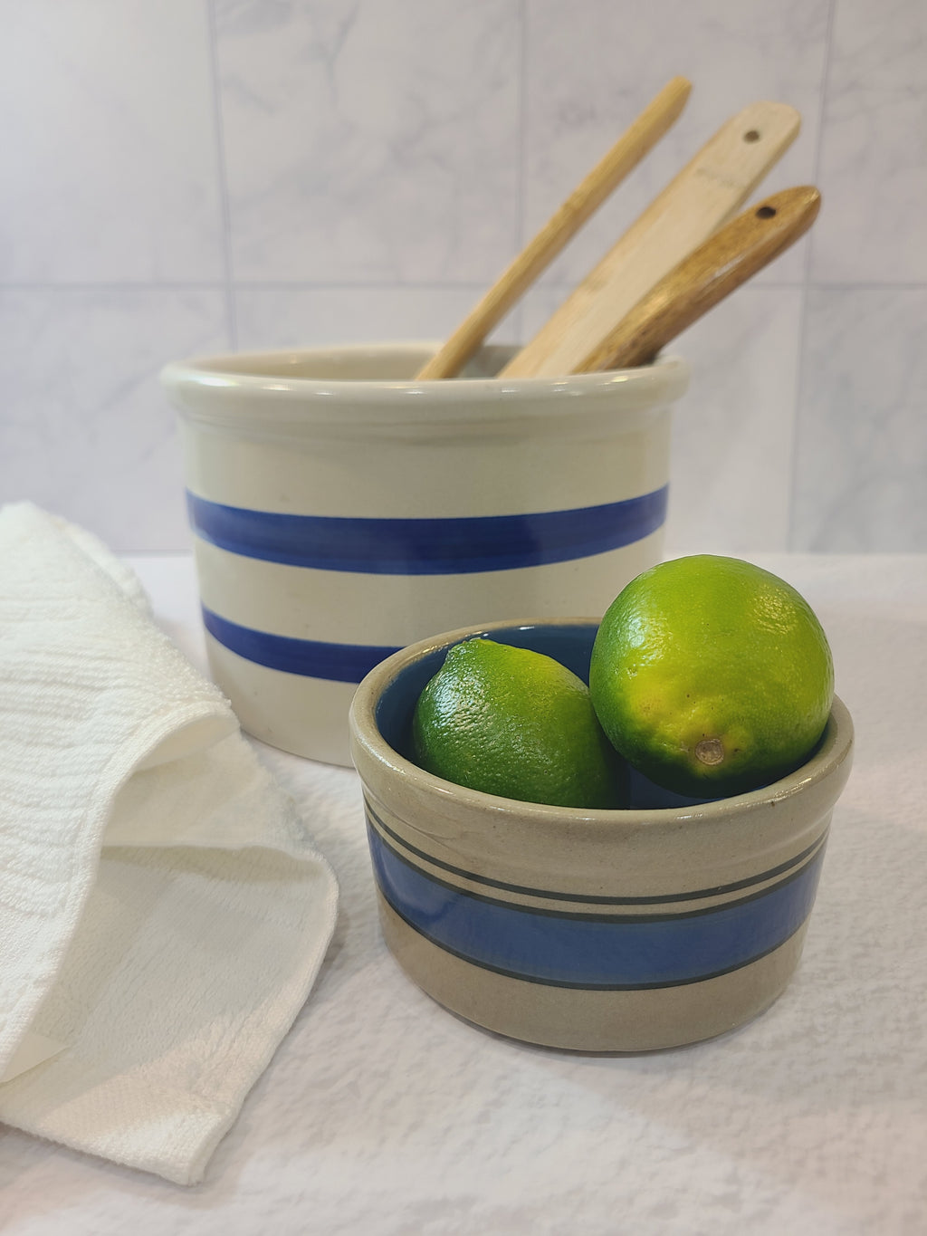 Vintage Robinson Ransbottom Pottery Off-white and Blue Crock holding wooden utensils shown with smaller gray and blue crock.
