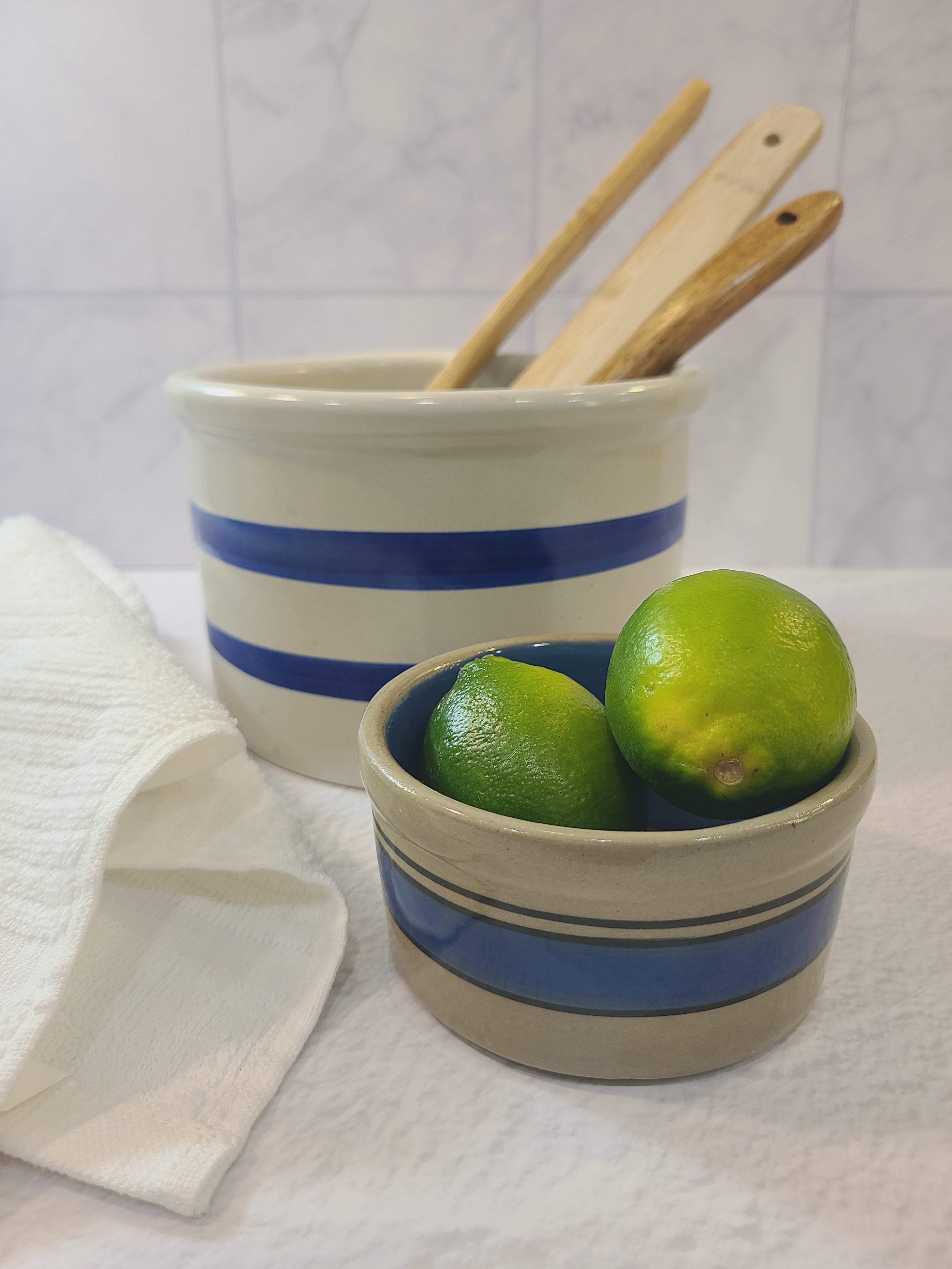Vintage Robinson Ransbottom Pottery Off-white and Blue Crock holding wooden utensils shown with smaller gray and blue crock.