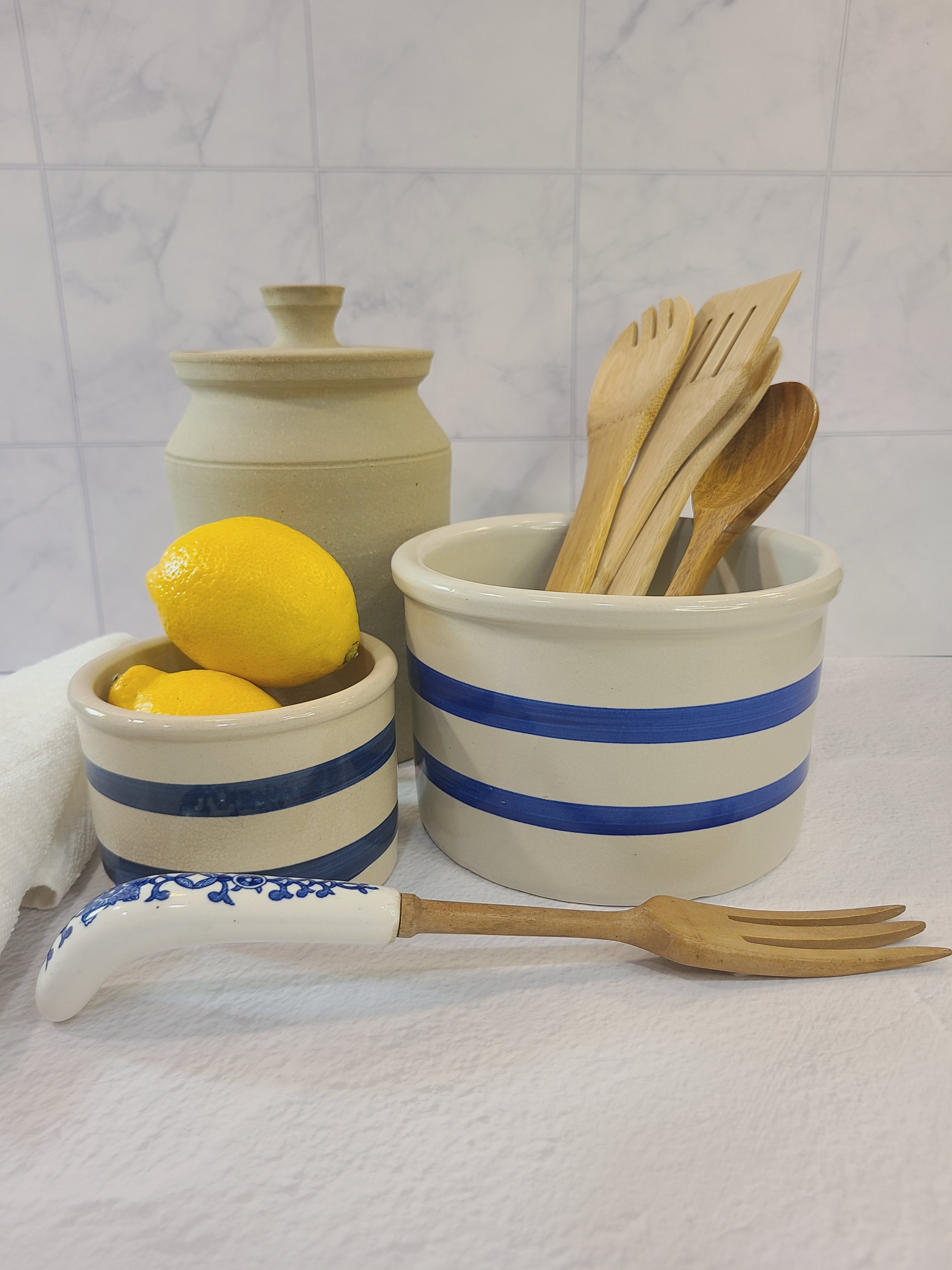 Vintage Robinson Ransbottom Pottery Off-white and Blue Crock displayed with a smaller crock, lemons, and natural lidded jar.
