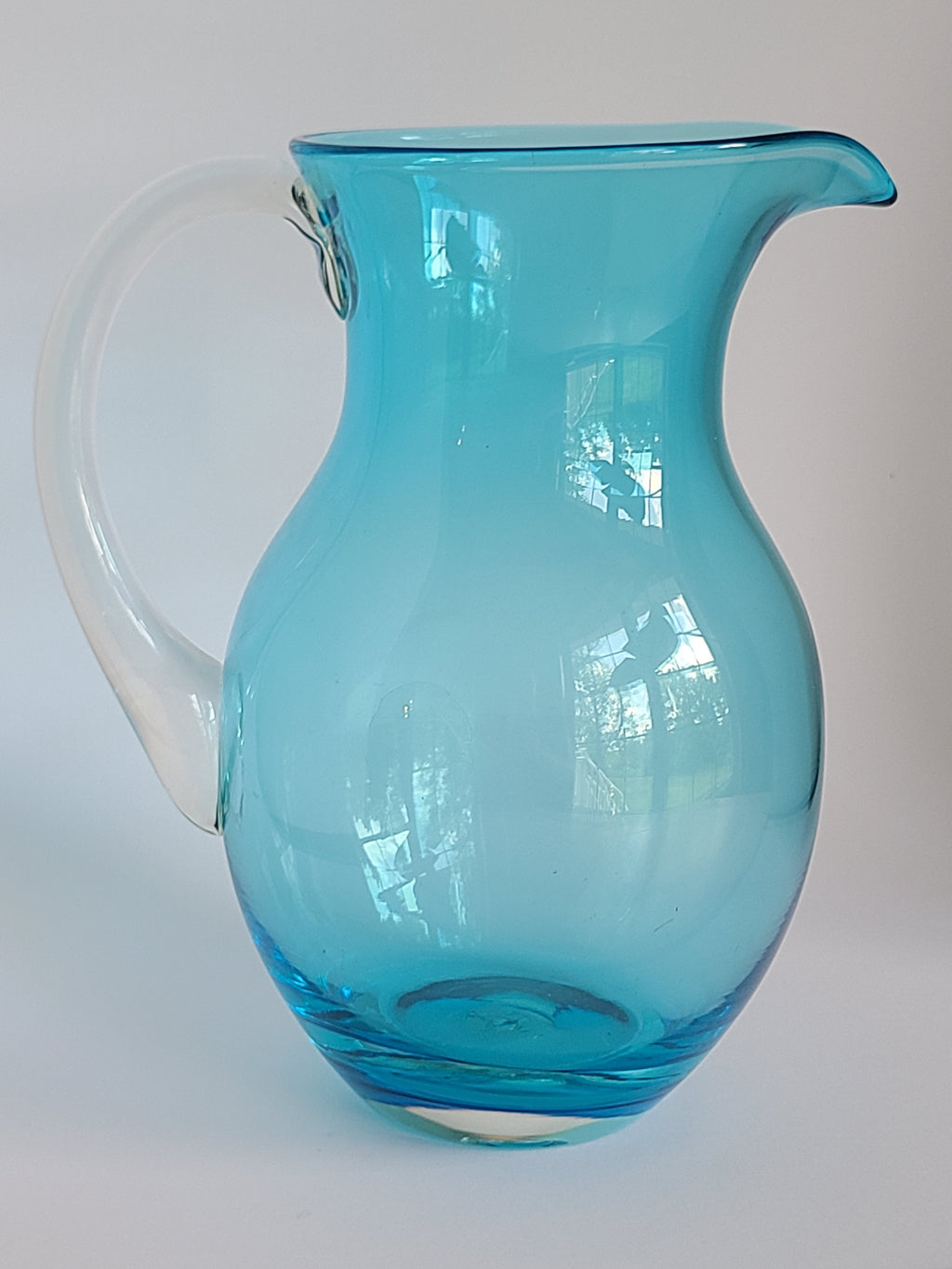 Side view of Turquoise glass vase with clear glass handle showing reflections.