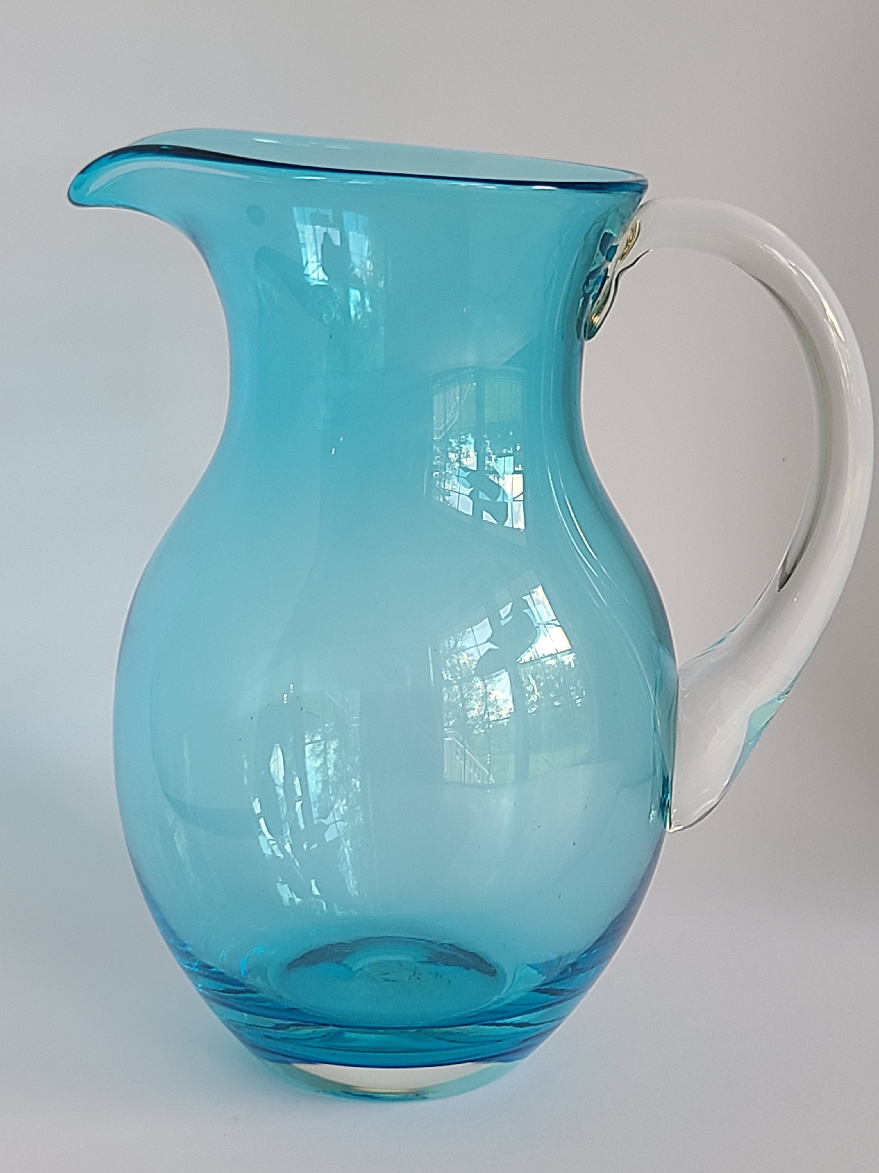 Turquoise glass vase with clear glass handle showing reflections.