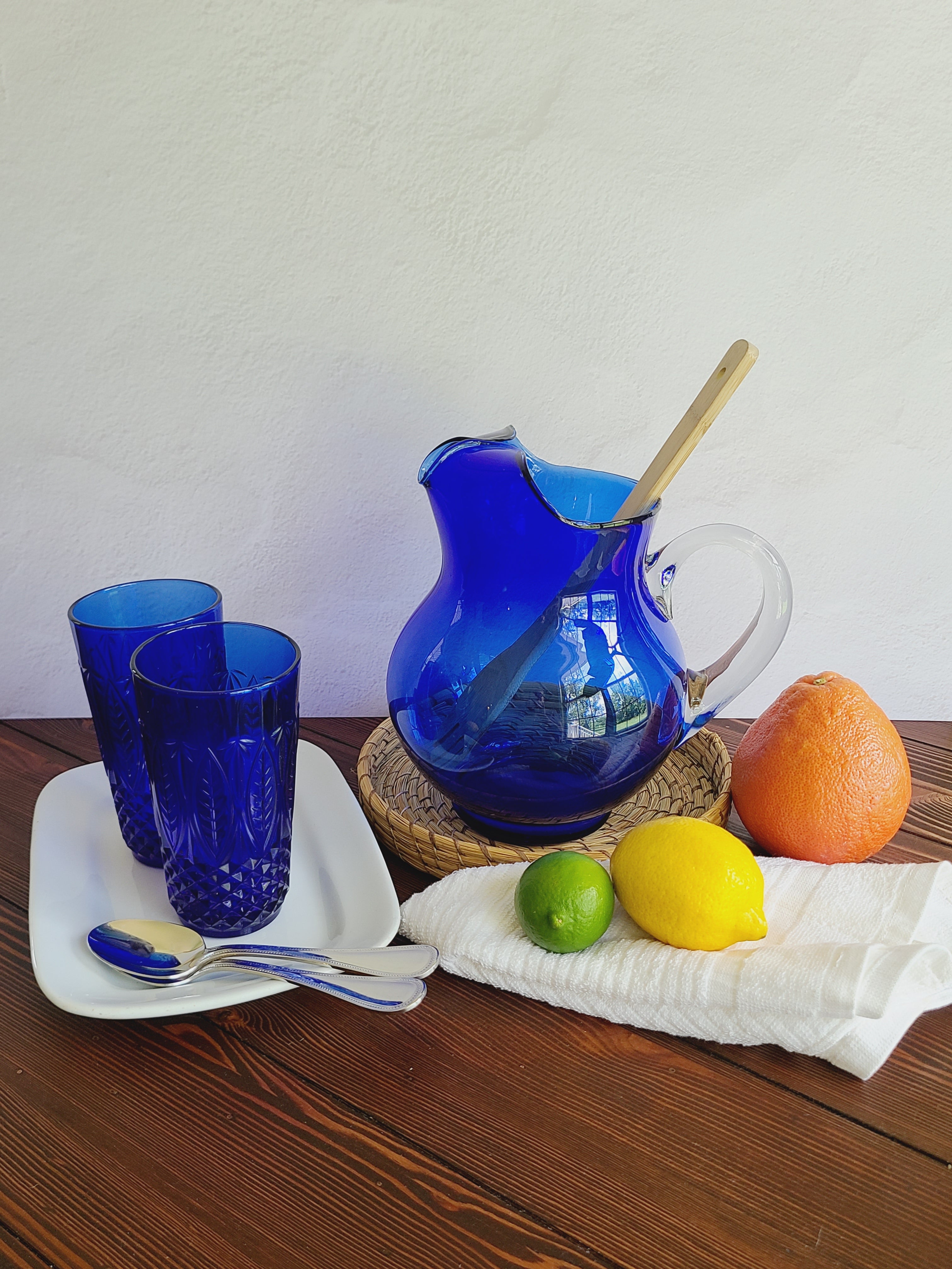 Antique white Alfred Meakin Royal Ironstone Platter in a table setting including cobalt blue glasses and pitcher, citrus fruit, silverware.