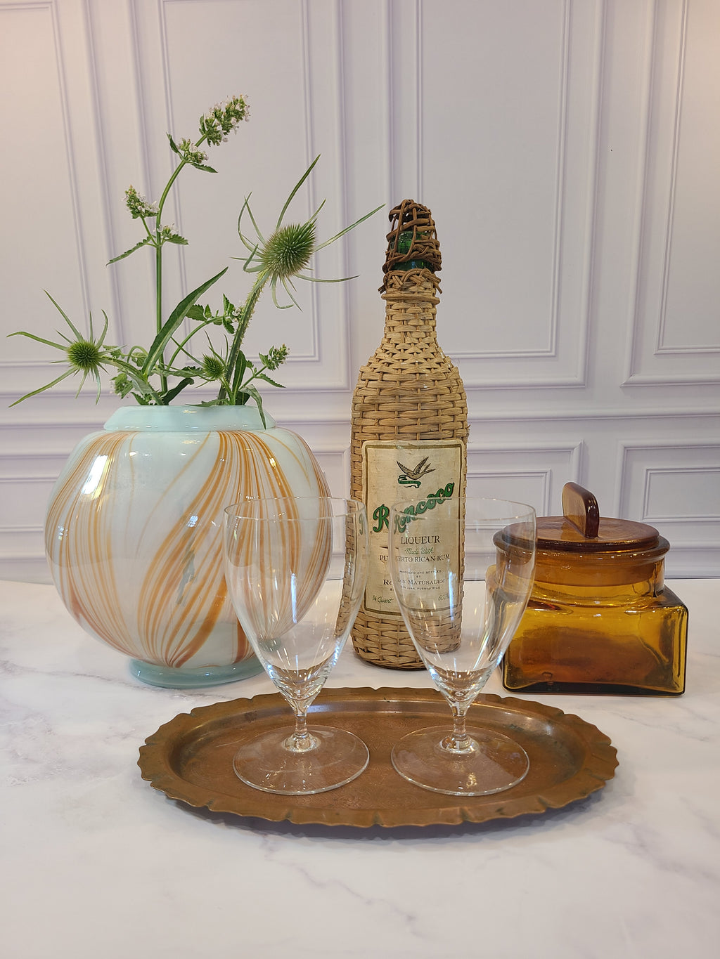 Handblown artisan glass vase in shape of a sphere, very pale aqua with orange feather-raked accents, 7 inches diameter, displayed with a decorative wine bottle wrapped in rattan, an amber glass jar, and two clear stemmed glasses on a copper tray.