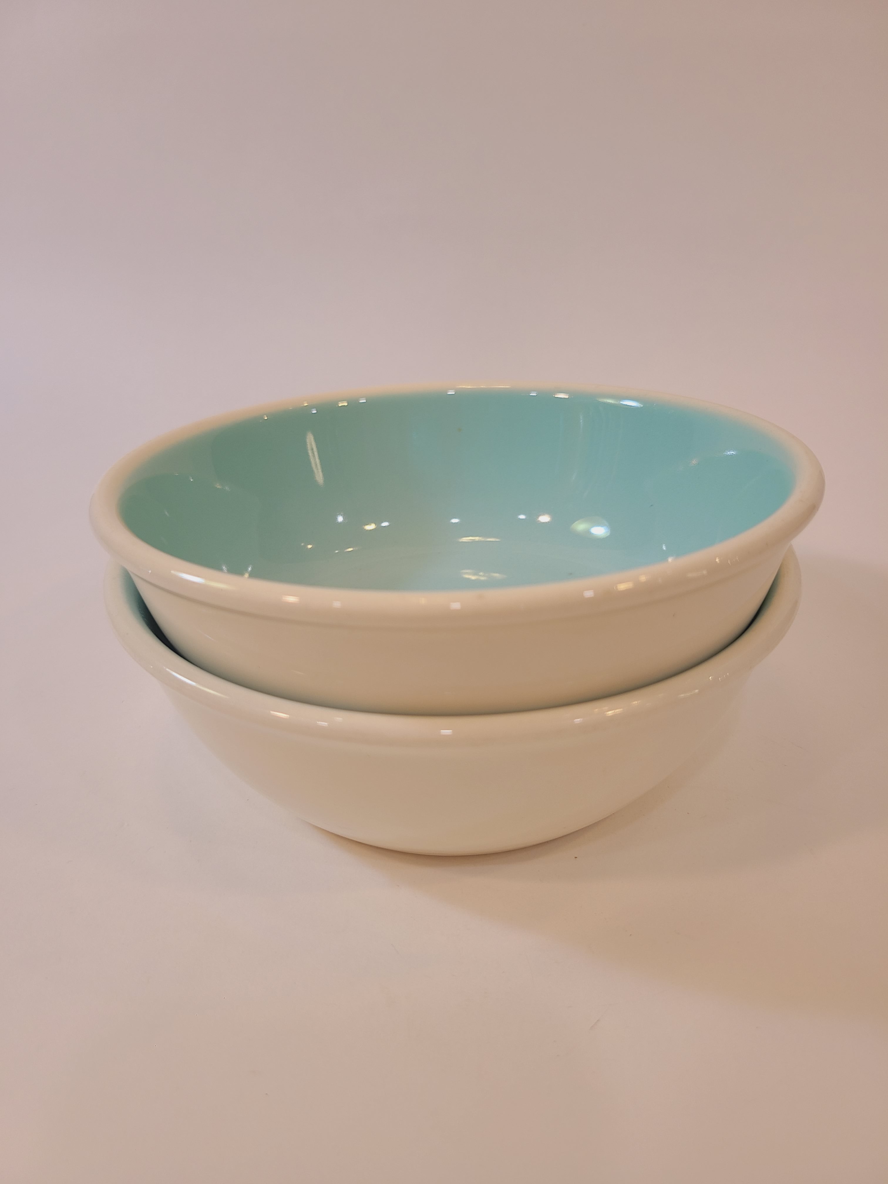 Two stacked vintage Chateau Buffet Stoneware Bowls with turquoise interior and white exterior.