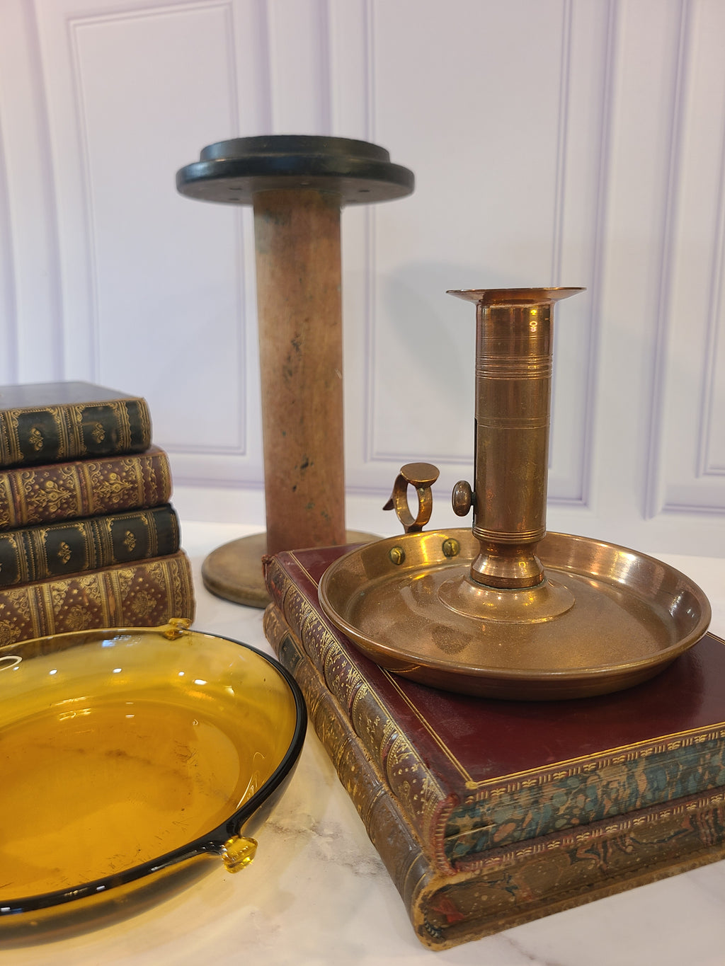 Antique Copper Candle Holder with Push-Up Lever displayed with antique books, glass bowls, and industrial spool