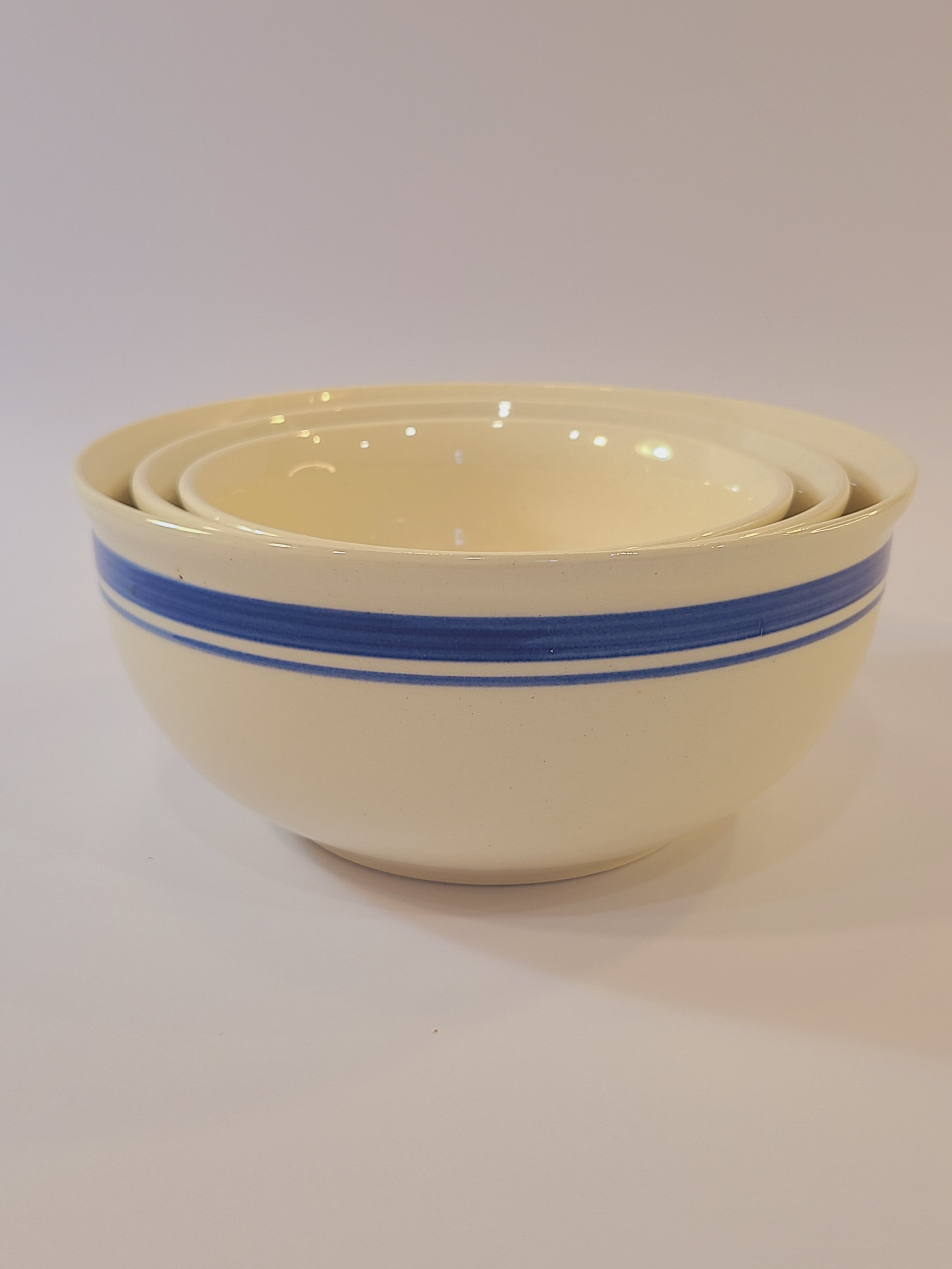 Set of three vintage nesting cream-colored ceramic bowls with blue stripes made in East Germany DDR.