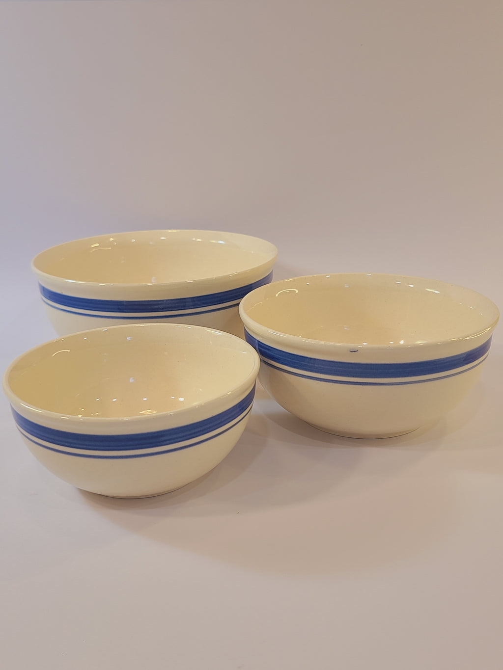 Three vintage cream-colored ceramic bowls with blue stripes made in East Germany DDR.