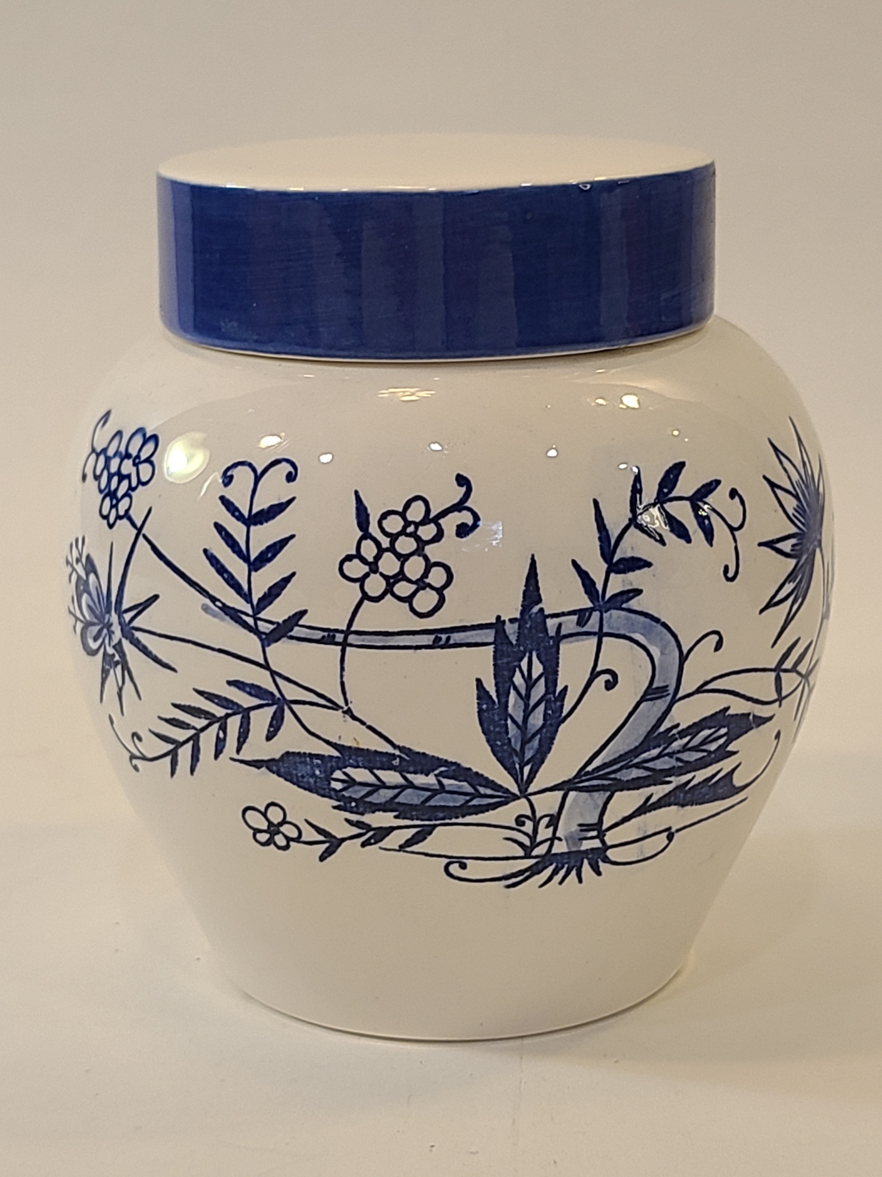 A vintage Japanese white ceramic tea jar with a blue floral hand-painted pattern and a blue and white lid, shown on a plain light background.