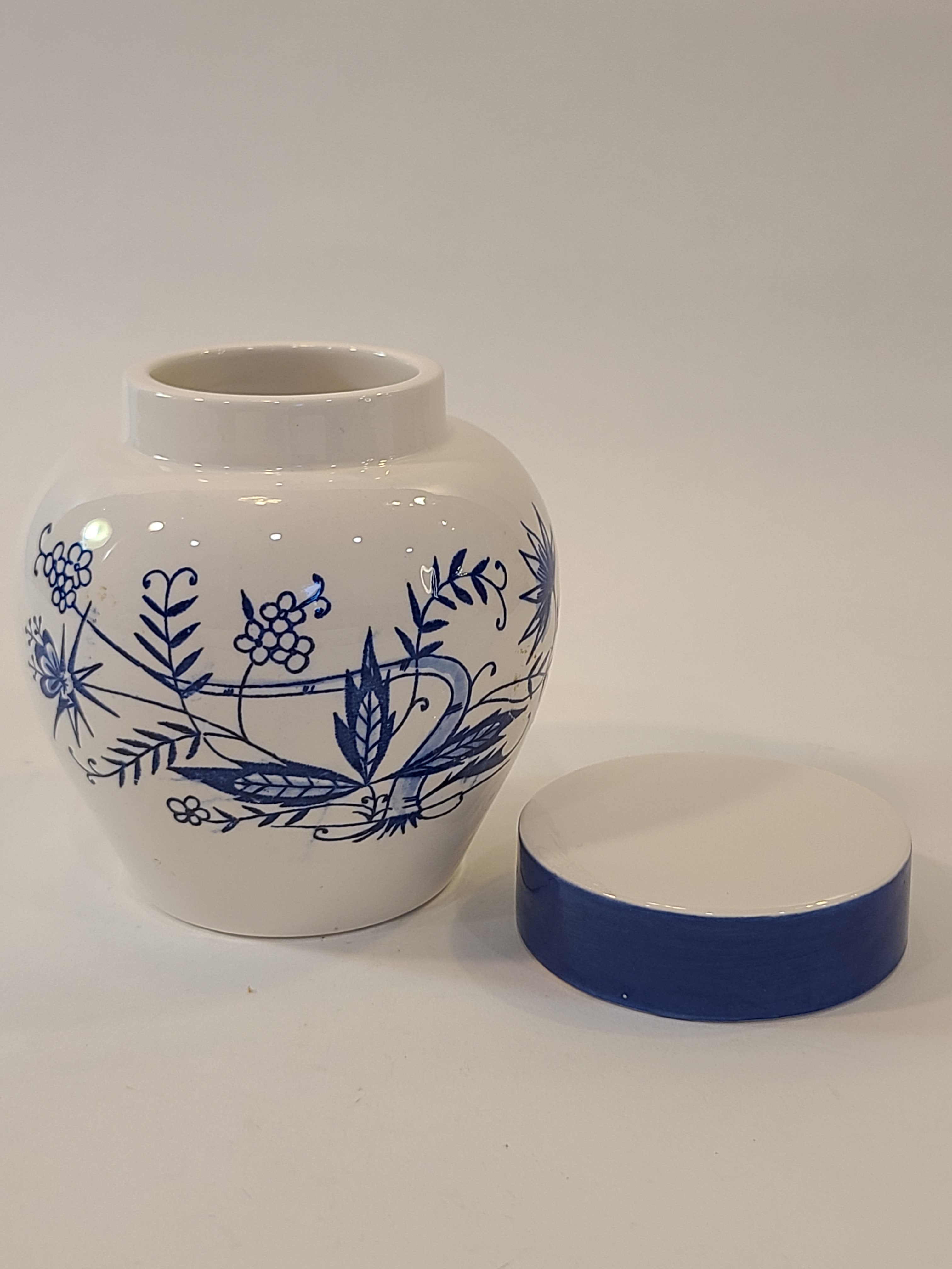 A vintage Japanese white ceramic tea jar with a blue floral hand-painted pattern shown with its matching blue and white lid.