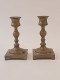 A pair of vintage brass candle holders with square bases, shown vertically against a plain off-white background.