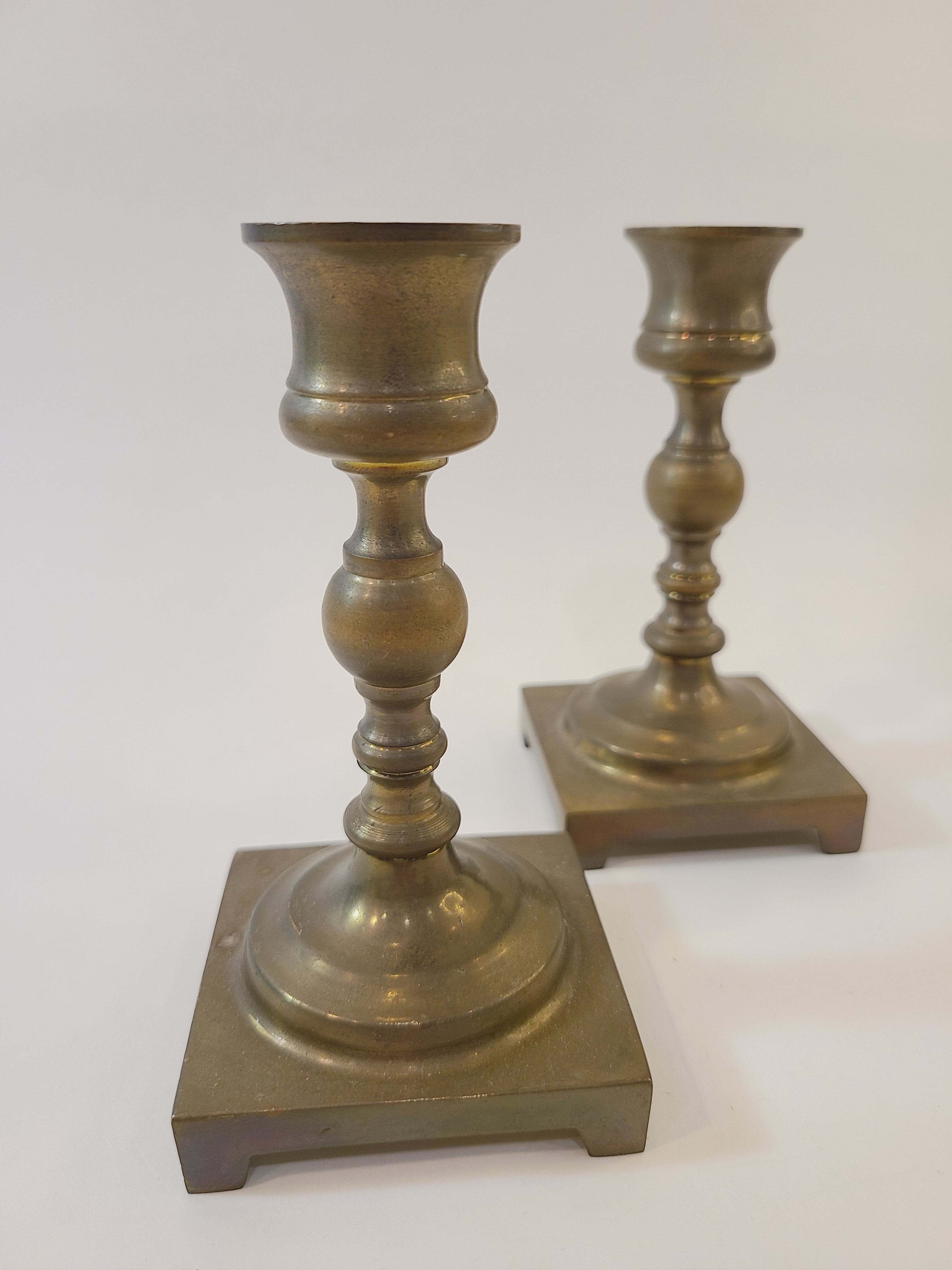 A pair of vintage brass candle holders with square bases.