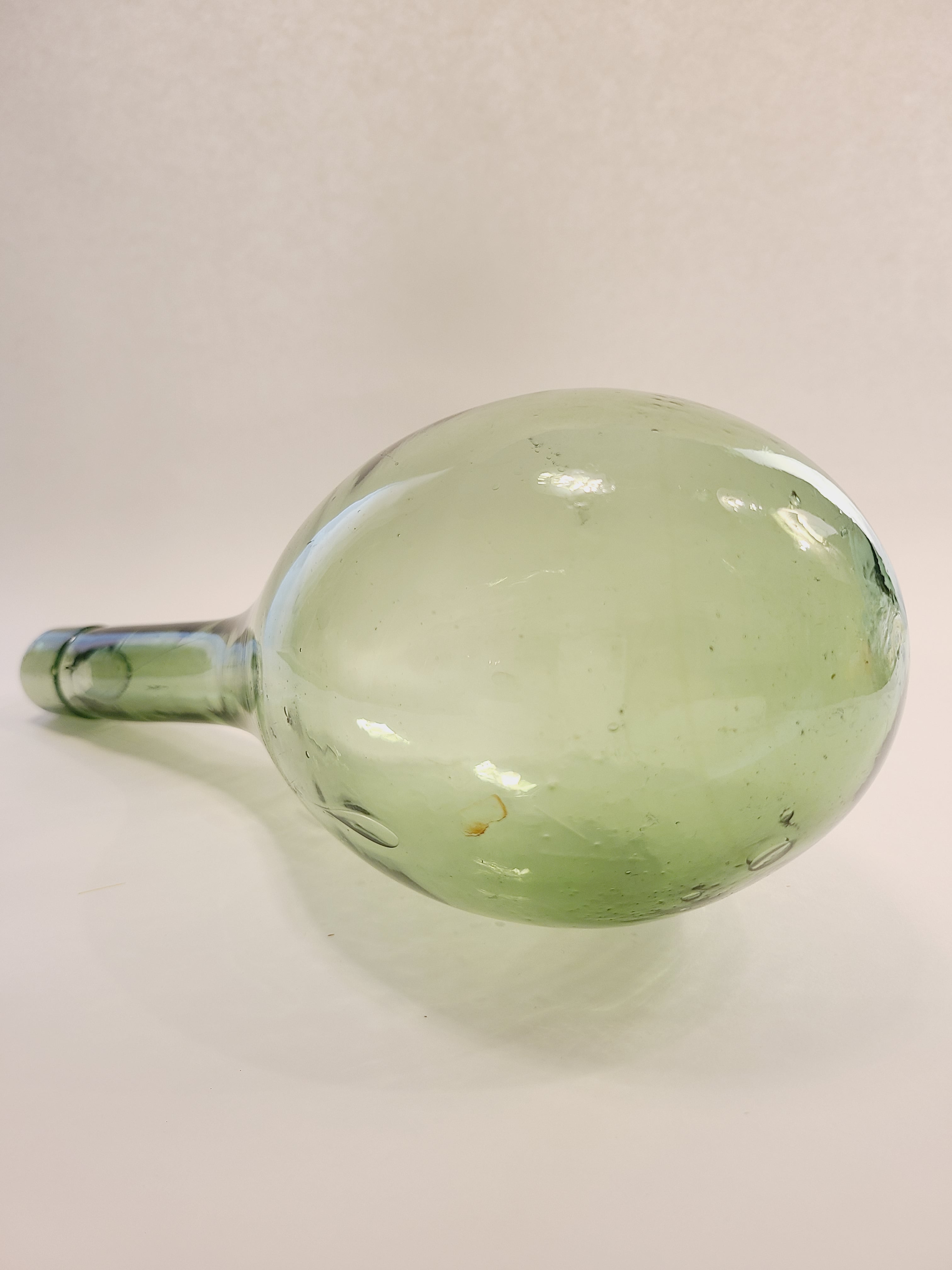 A vintage light green glass bottle with a bulbous round bottom.