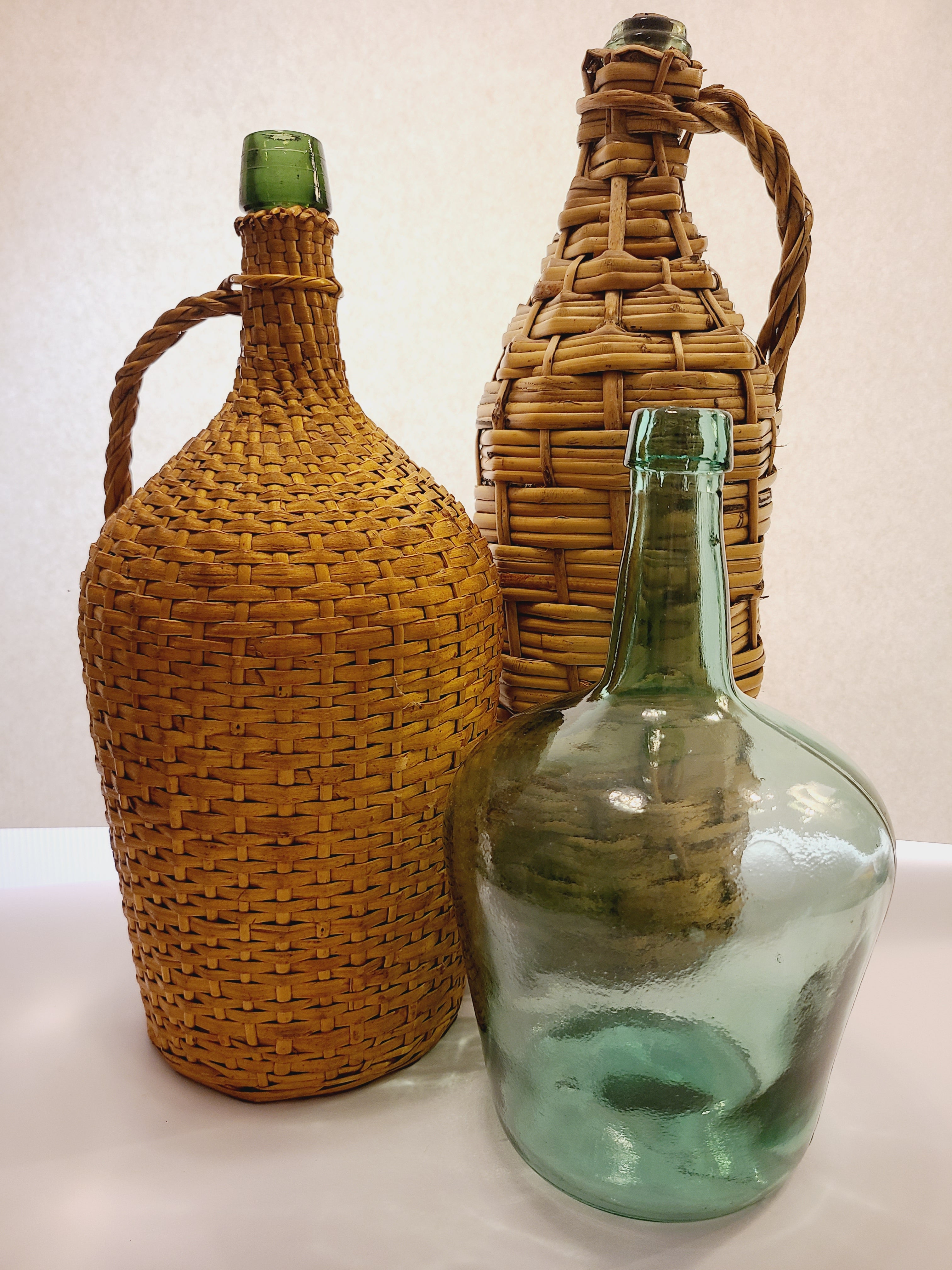 Vintage Green Glass Demijohn 10" shown with two other demijohns with wicker casing